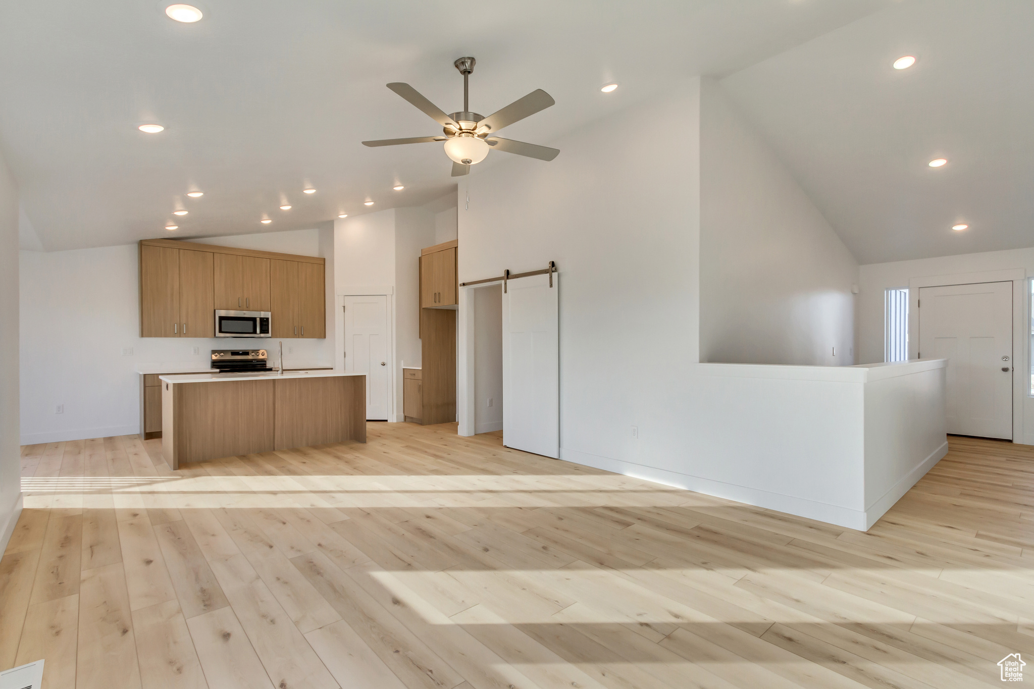 Kitchen with a center island, light hardwood / wood-style flooring, ceiling fan, a barn door, and range