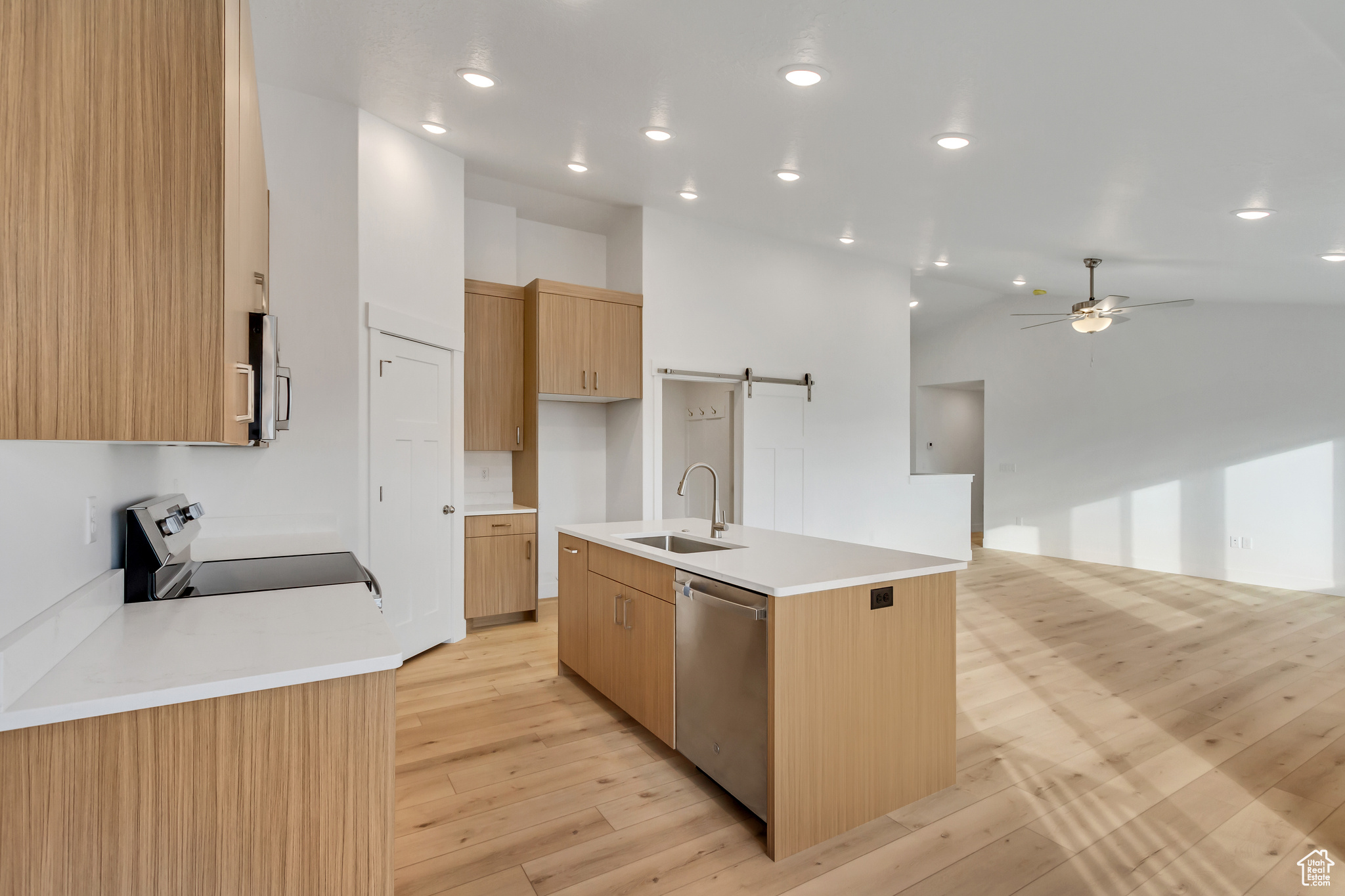 Kitchen with dishwasher, sink, a barn door, stove, and a kitchen island with sink