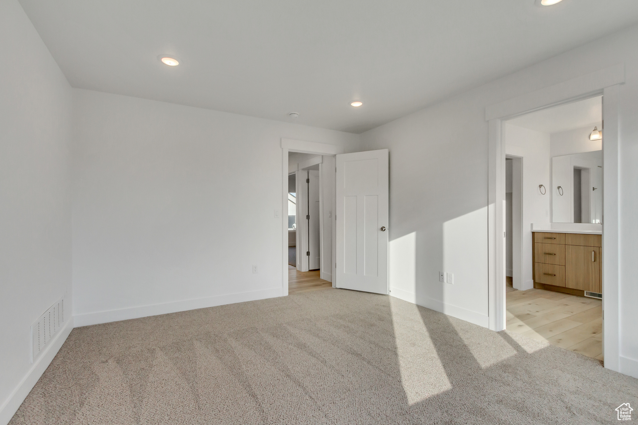 Unfurnished bedroom featuring light carpet and ensuite bathroom