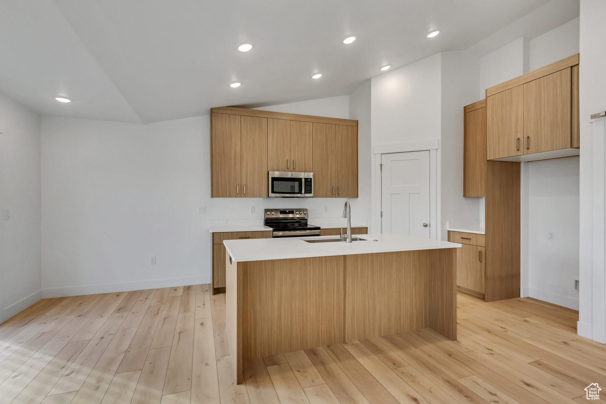 Kitchen featuring sink, an island with sink, vaulted ceiling, and appliances with stainless steel finishes