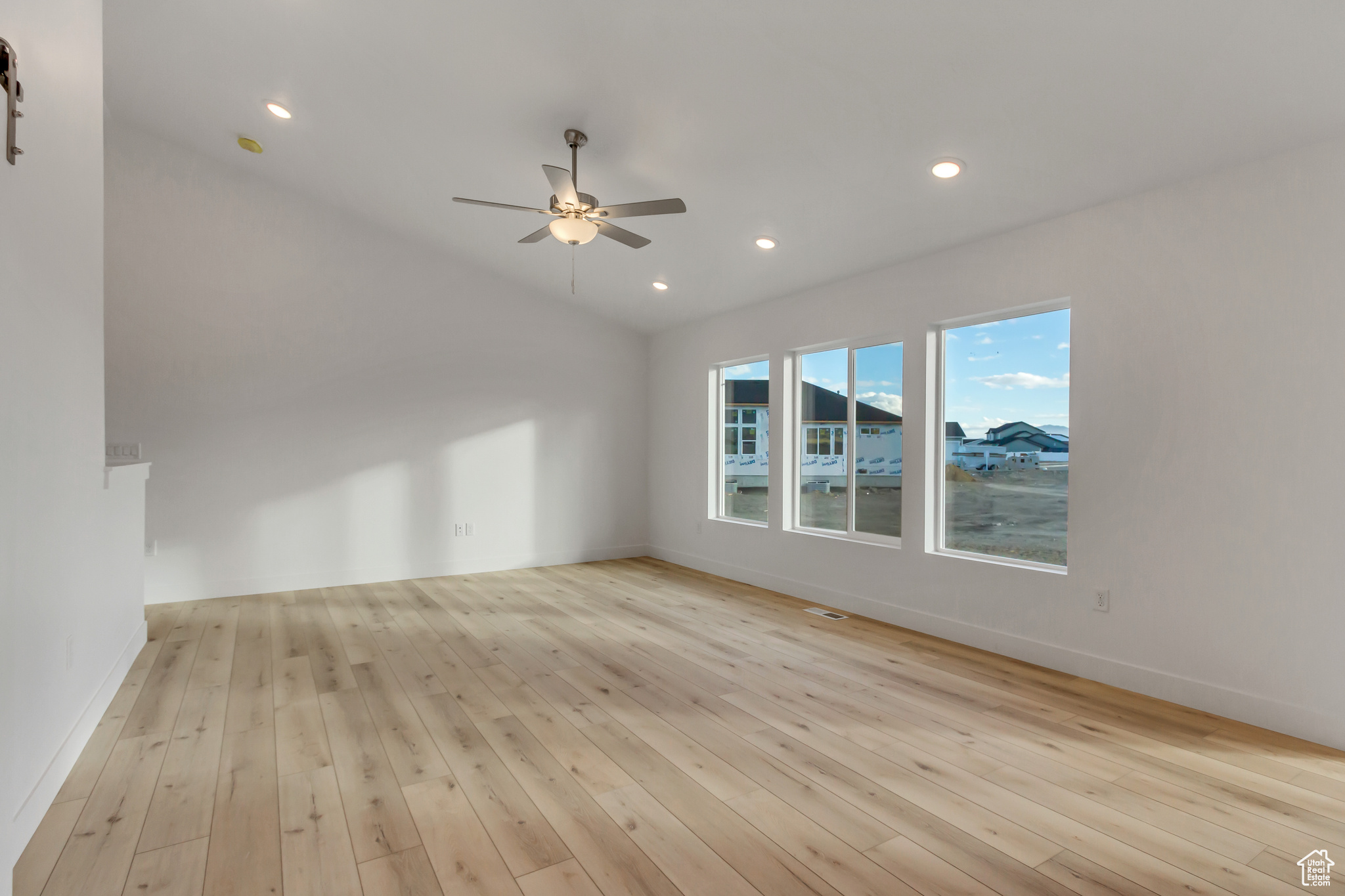 Spare room featuring ceiling fan, light hardwood / wood-style floors, and vaulted ceiling