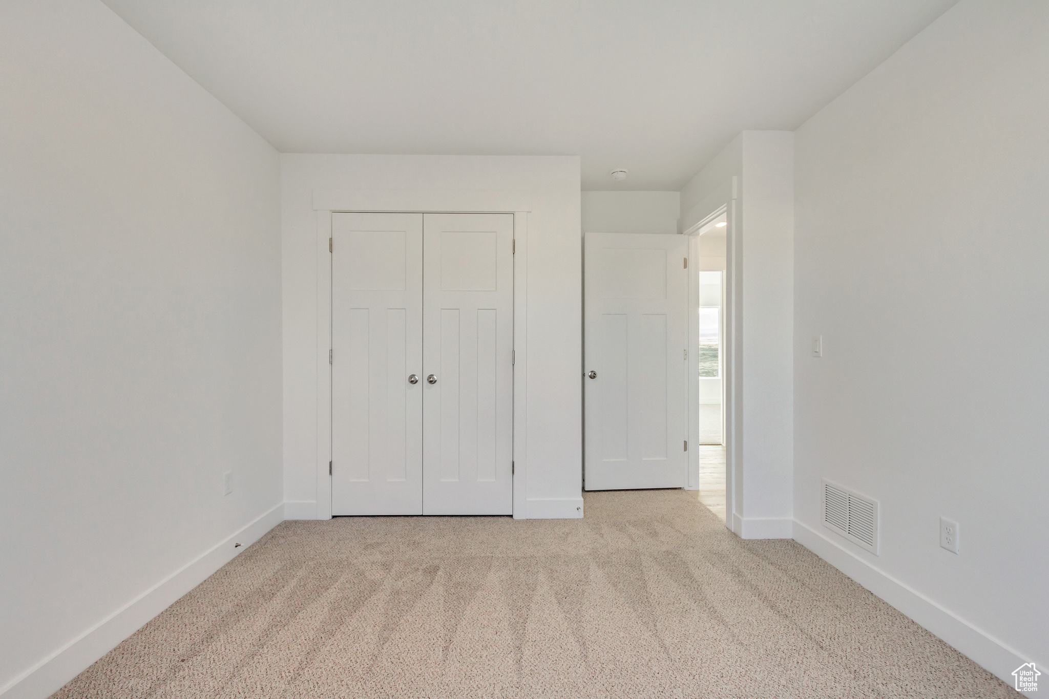 Unfurnished bedroom featuring light carpet and a closet