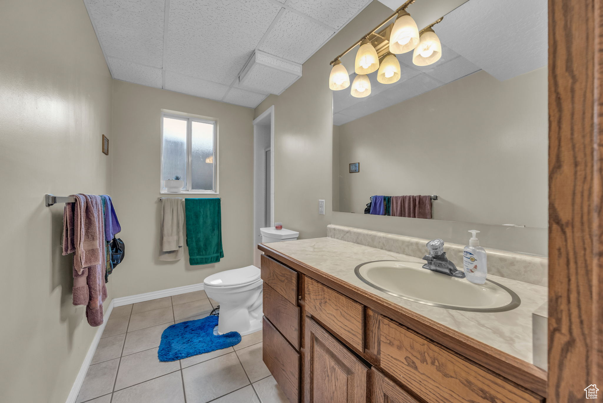 Bathroom featuring a paneled ceiling, vanity, toilet, and tile patterned floors