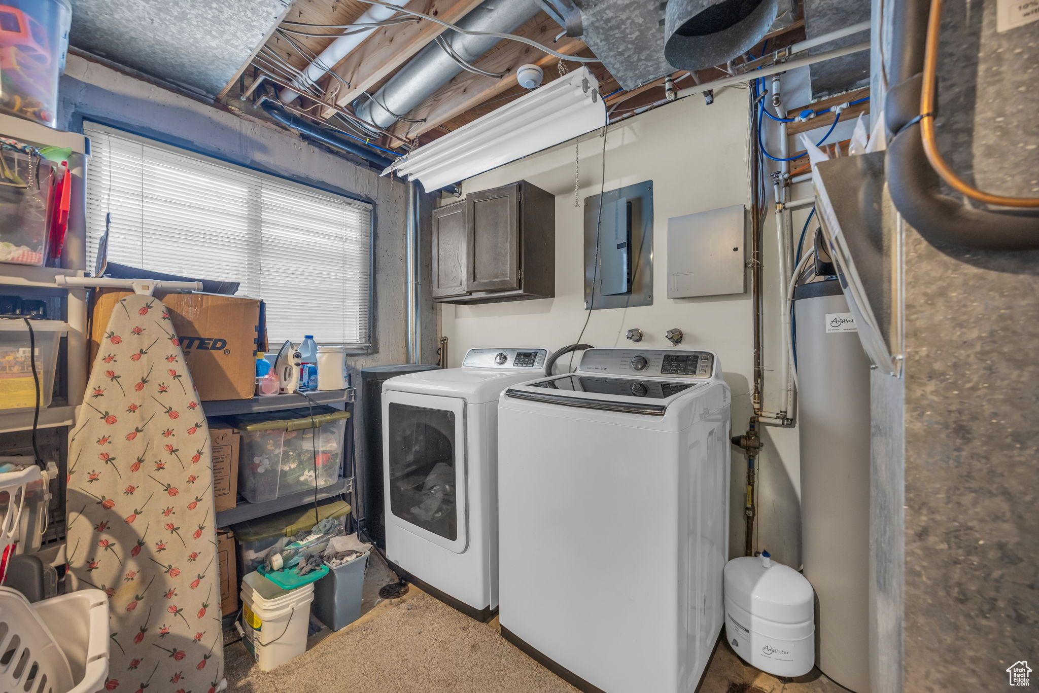 Washroom featuring carpet flooring, electric panel, washer and clothes dryer, and cabinets