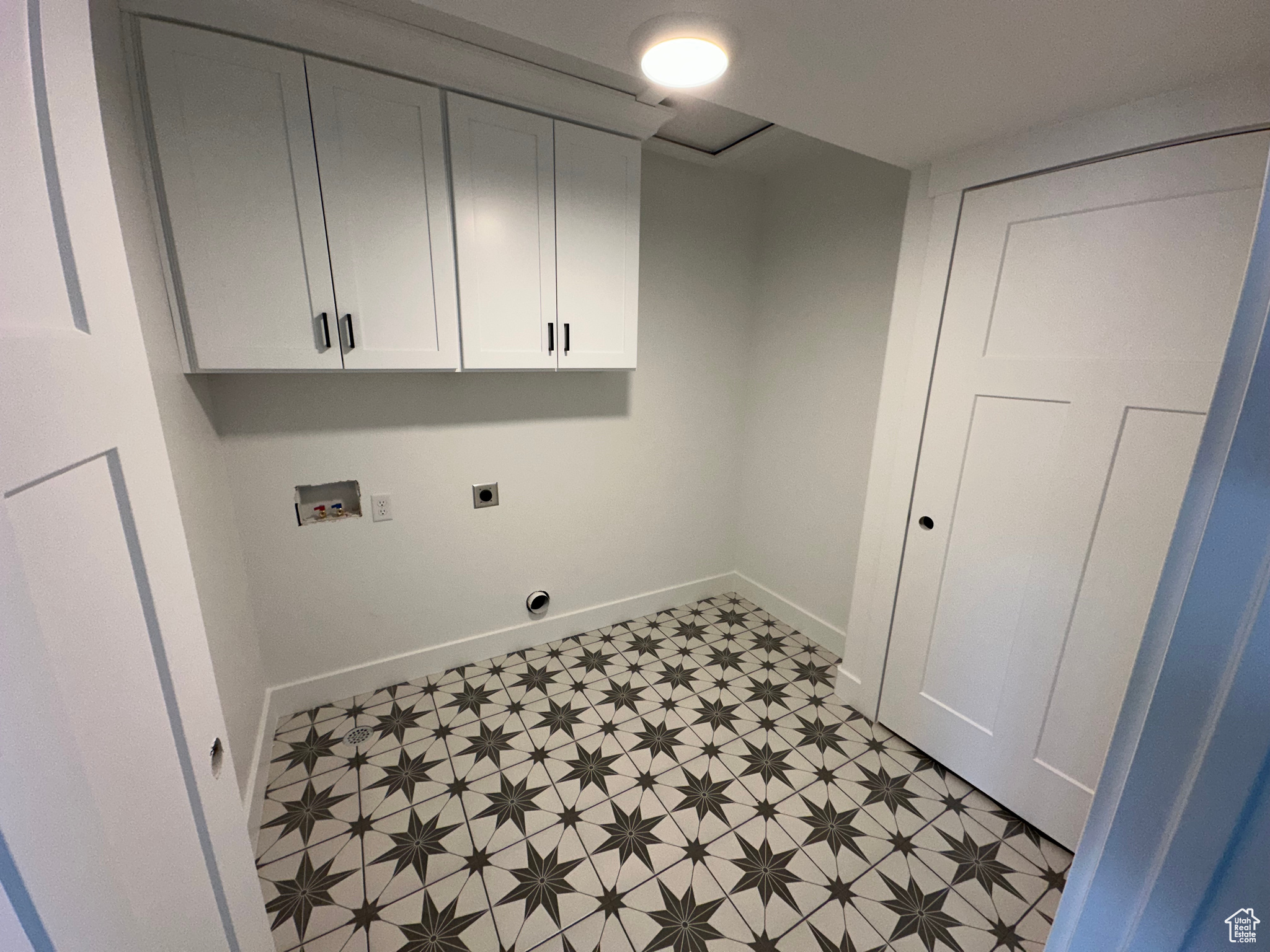 Second floor laundry room with tile flooring and cabinet storage.