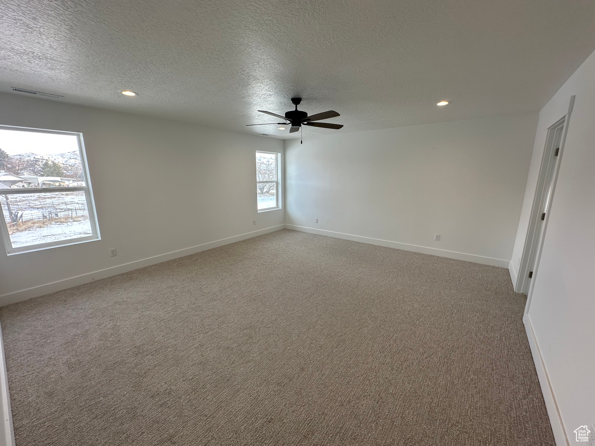 Large owner's bedroom with bedrooms wall window set and ceiling fan.