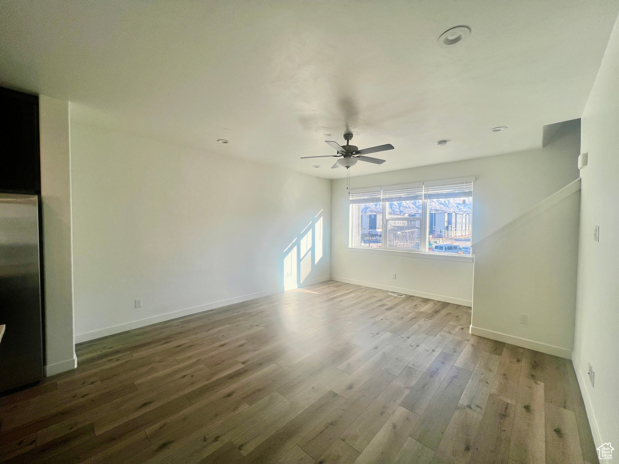 Unfurnished living room with wood-type flooring and ceiling fan