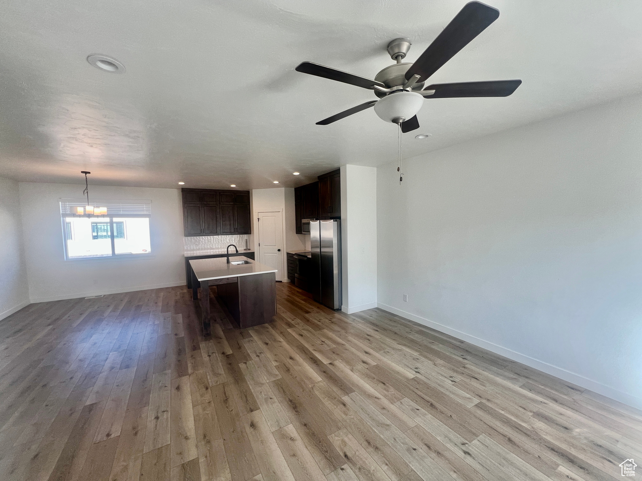 Unfurnished living room with hardwood / wood-style floors and ceiling fan with notable chandelier