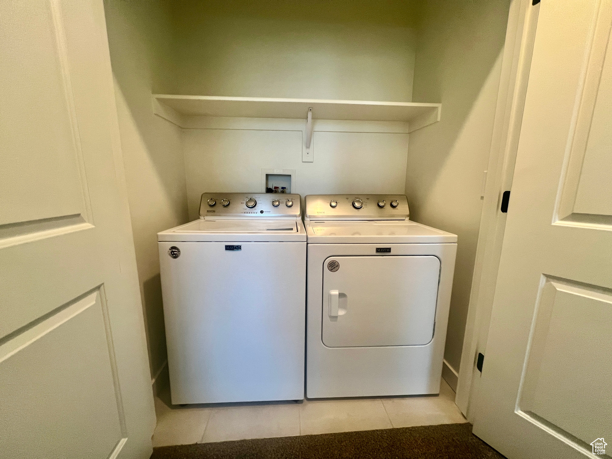 Laundry area featuring light tile patterned flooring and separate washer and dryer