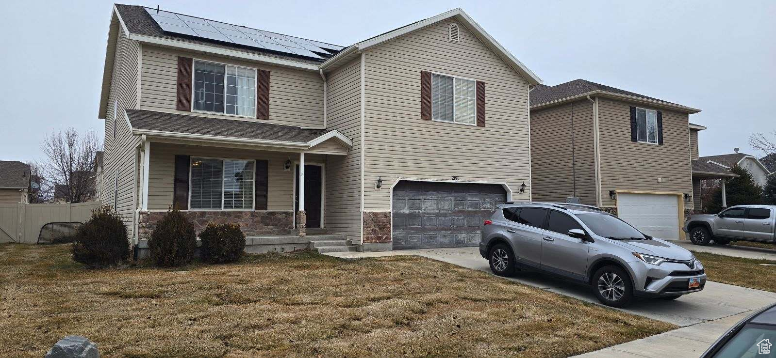 View of front of property with solar panels, a front lawn, and a garage