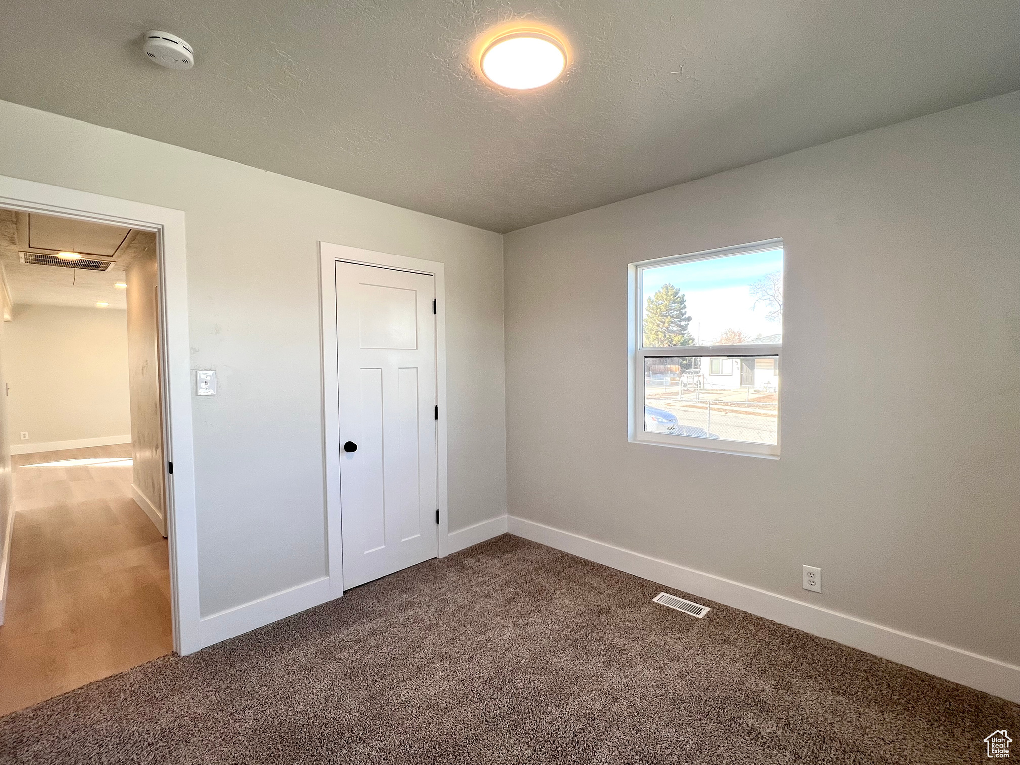 Unfurnished bedroom featuring carpet flooring, a textured ceiling, and a closet