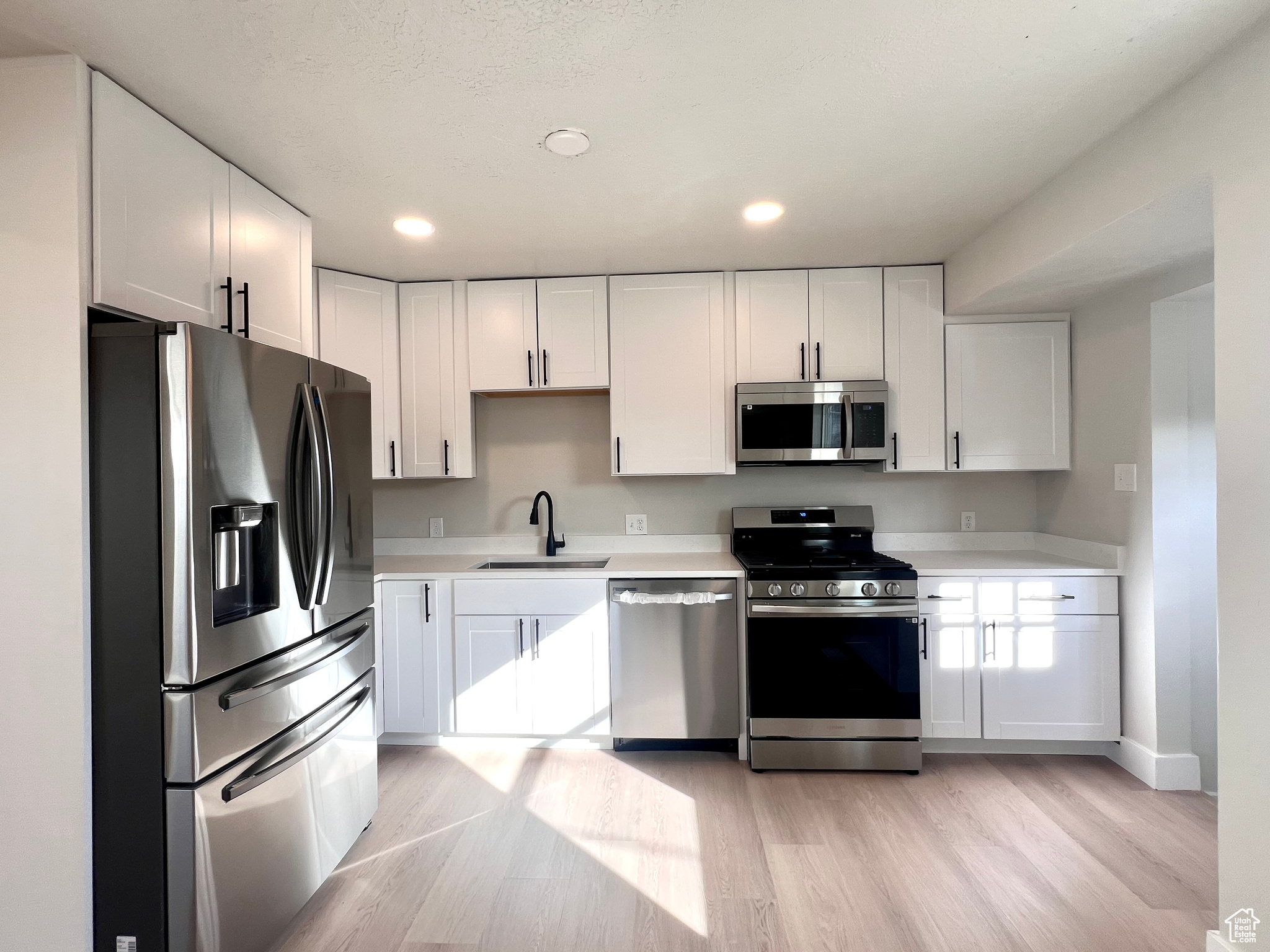 Kitchen with white cabinets, stainless steel appliances, and sink