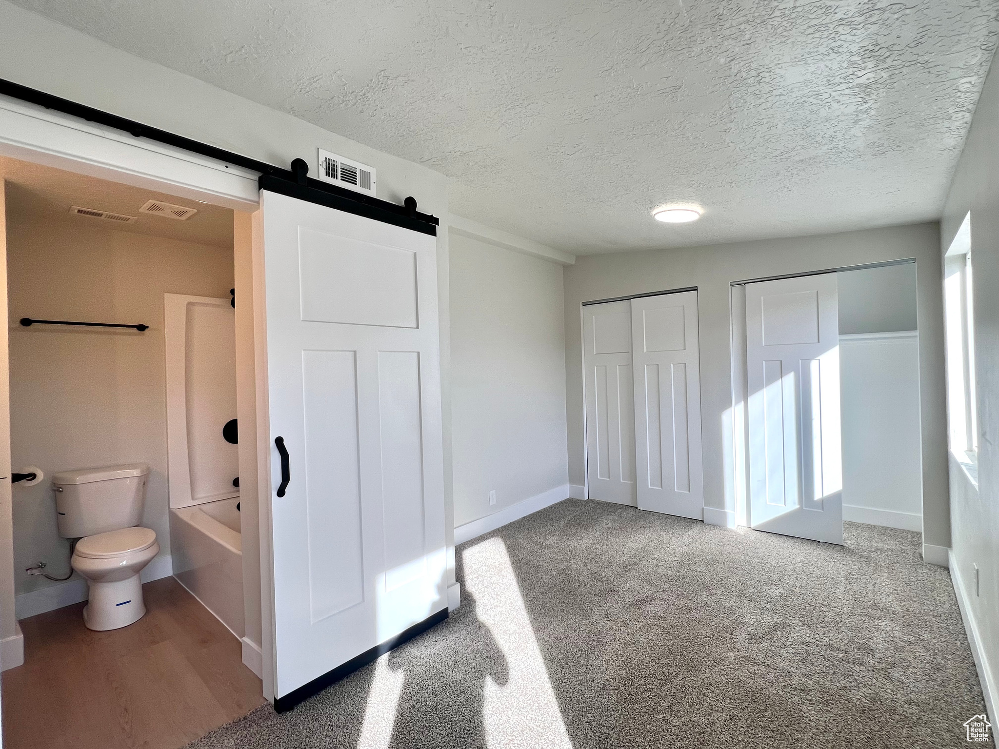 Bathroom featuring wood-type flooring, a textured ceiling, toilet, and shower / bathtub combination