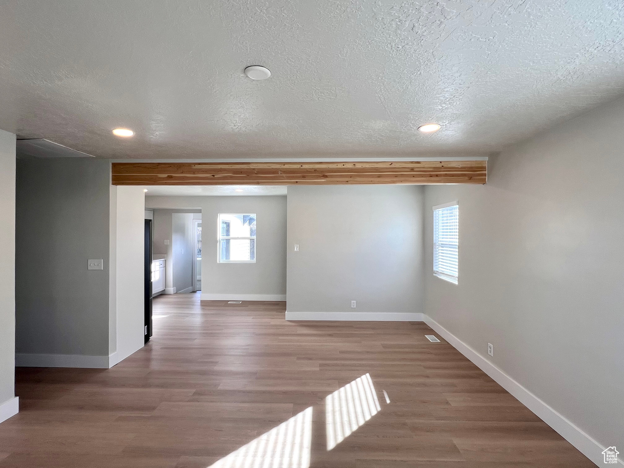 Empty room with a healthy amount of sunlight, a textured ceiling, and light wood-type flooring