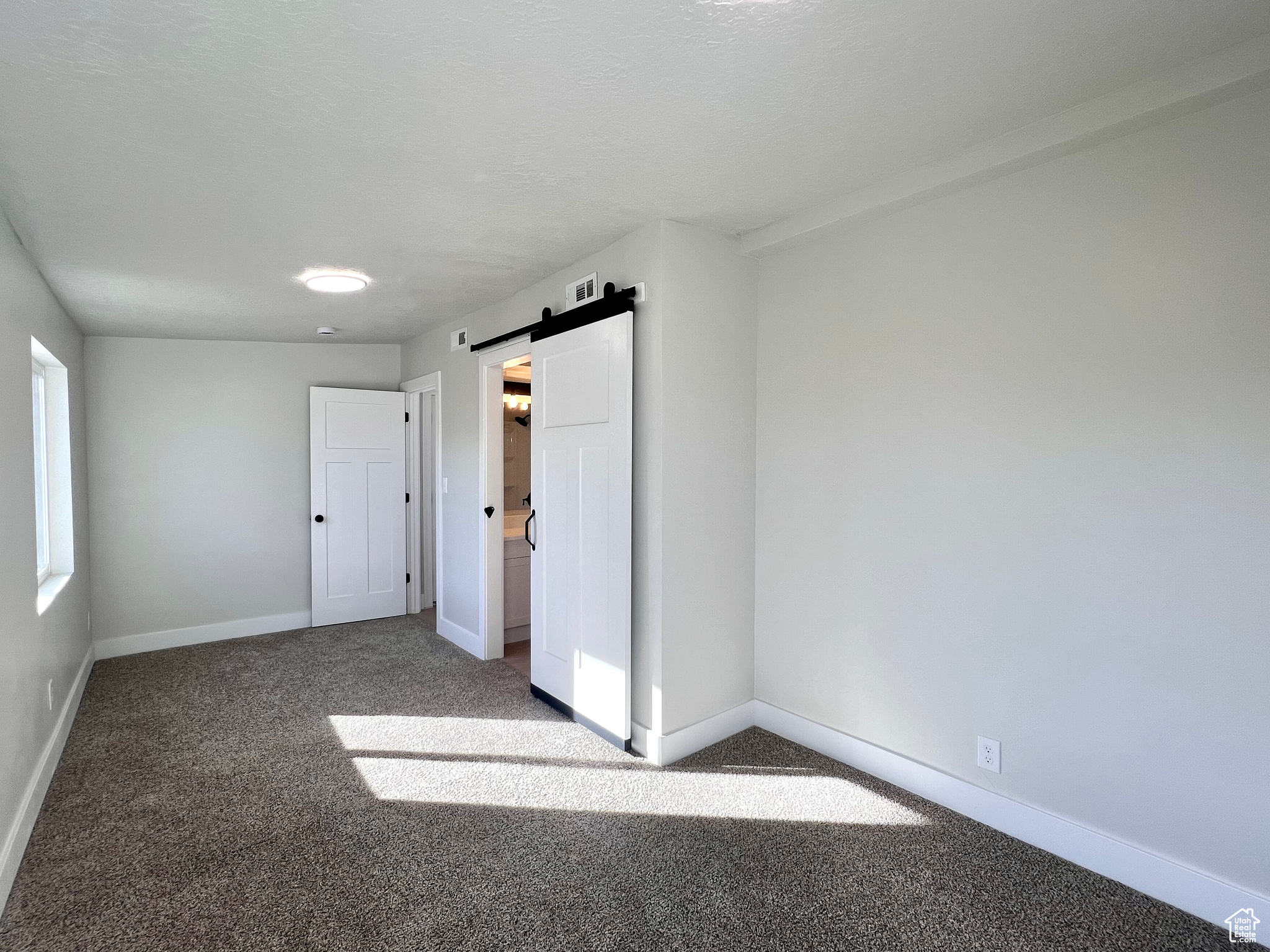 Unfurnished bedroom featuring carpet and a barn door