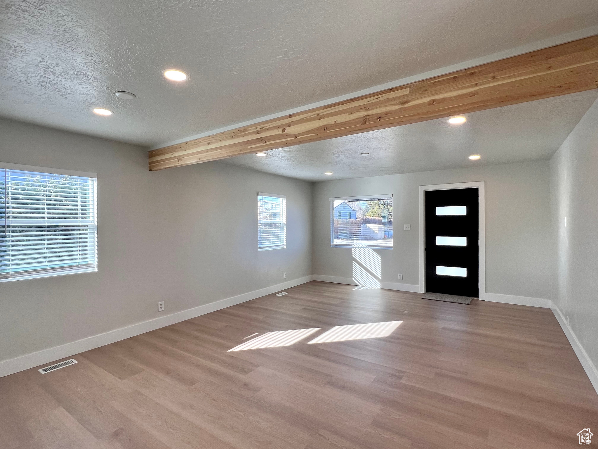 Foyer featuring beam ceiling, a textured ceiling, and light hardwood / wood-style flooring