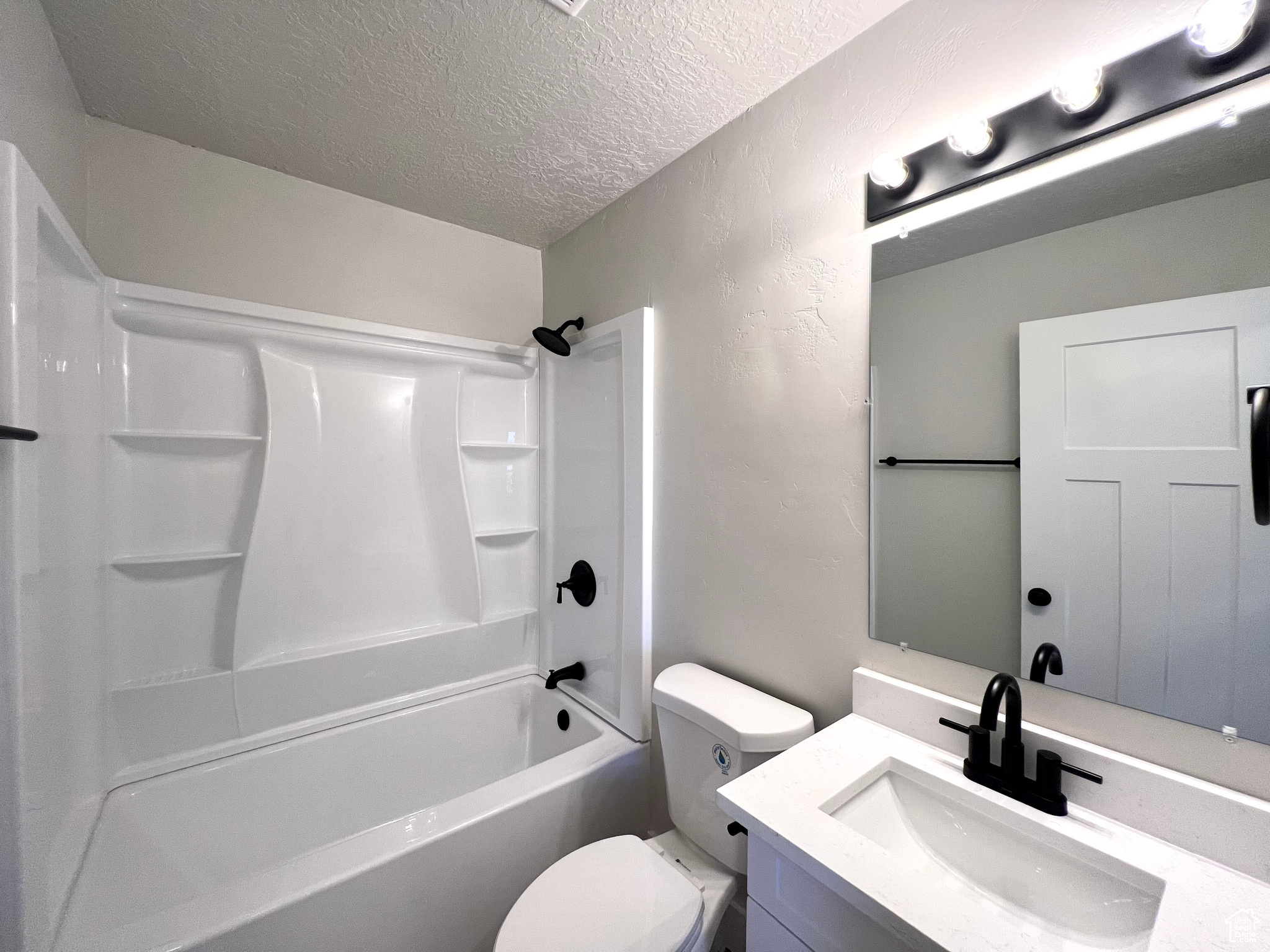 Full bathroom with vanity, toilet, a textured ceiling, and bathtub / shower combination