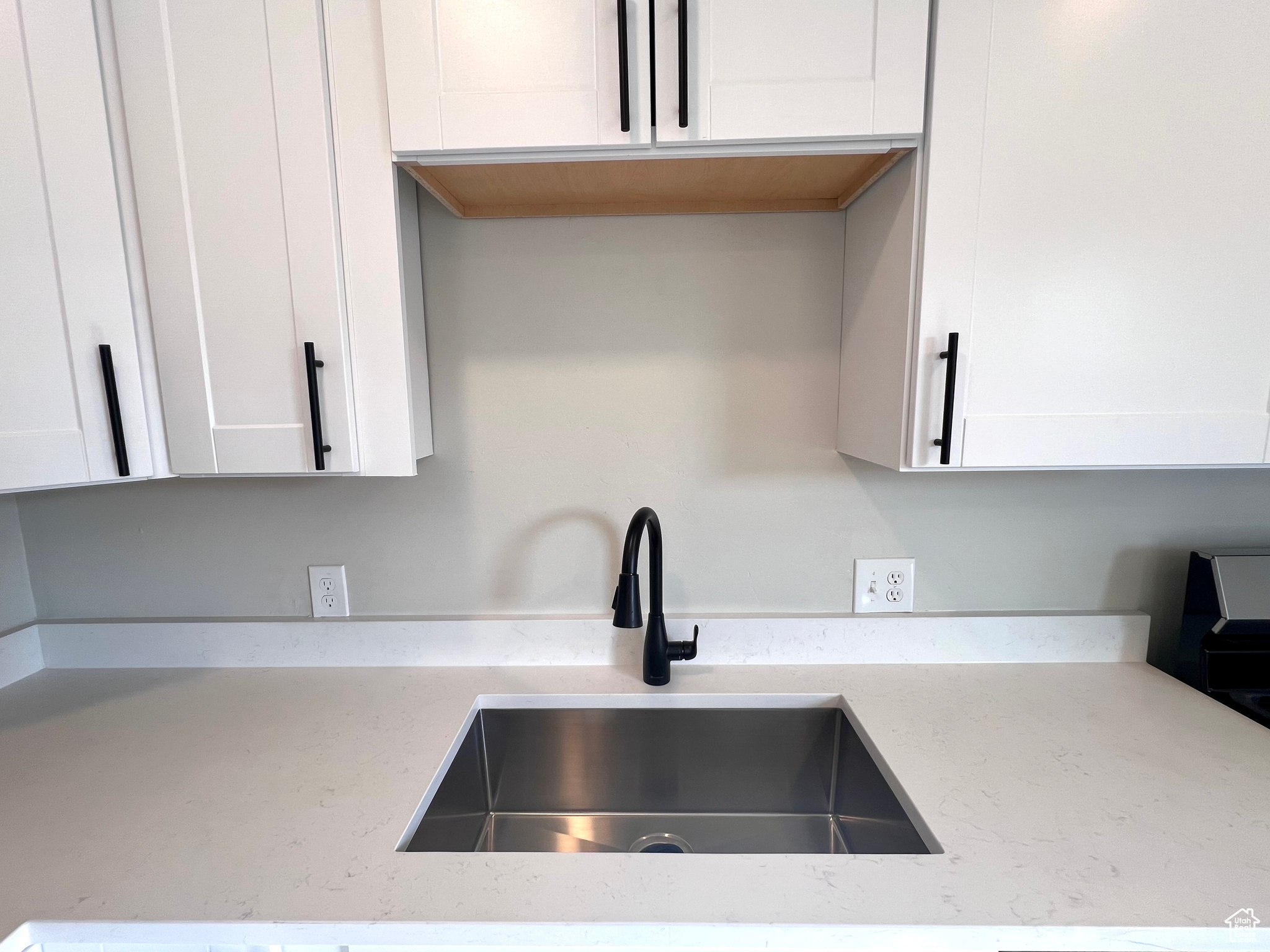 Kitchen with white cabinetry, sink, and light stone countertops