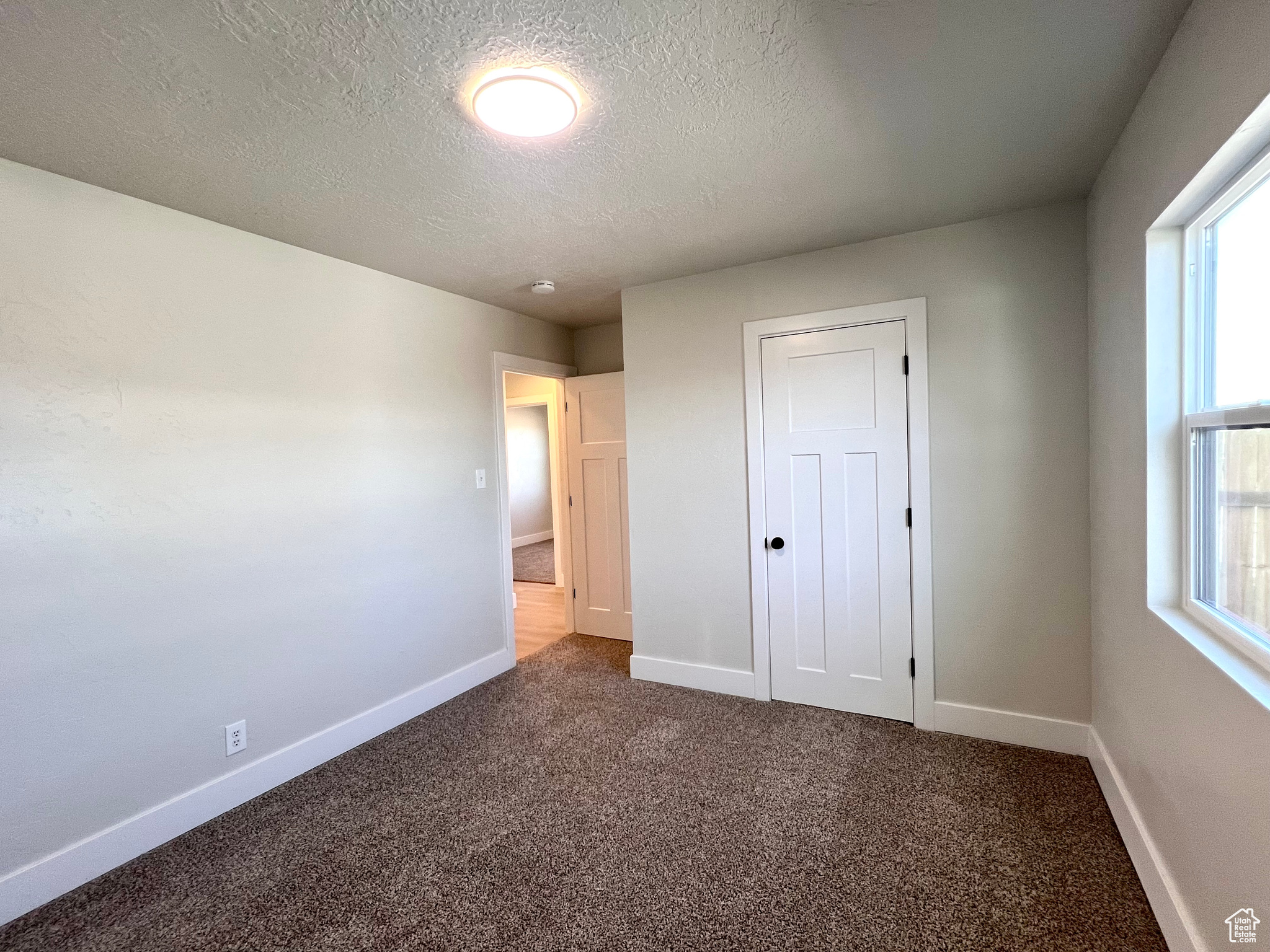 Unfurnished bedroom with carpet, a textured ceiling, and a closet