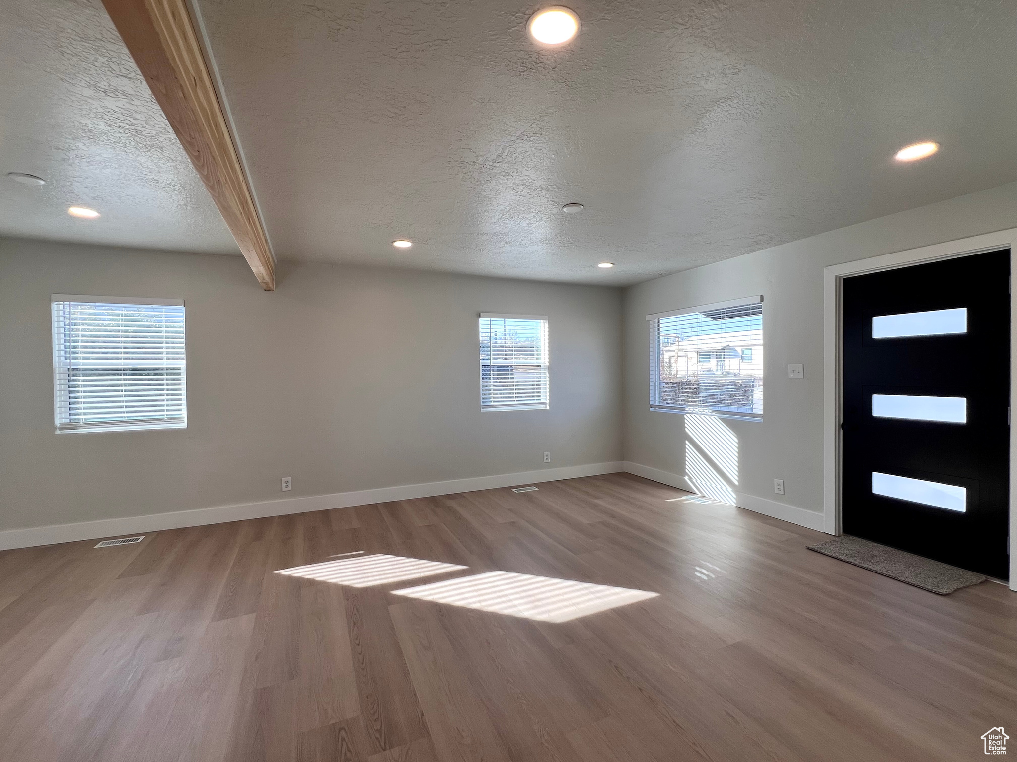 Entryway featuring beamed ceiling, a textured ceiling, and light wood-type flooring