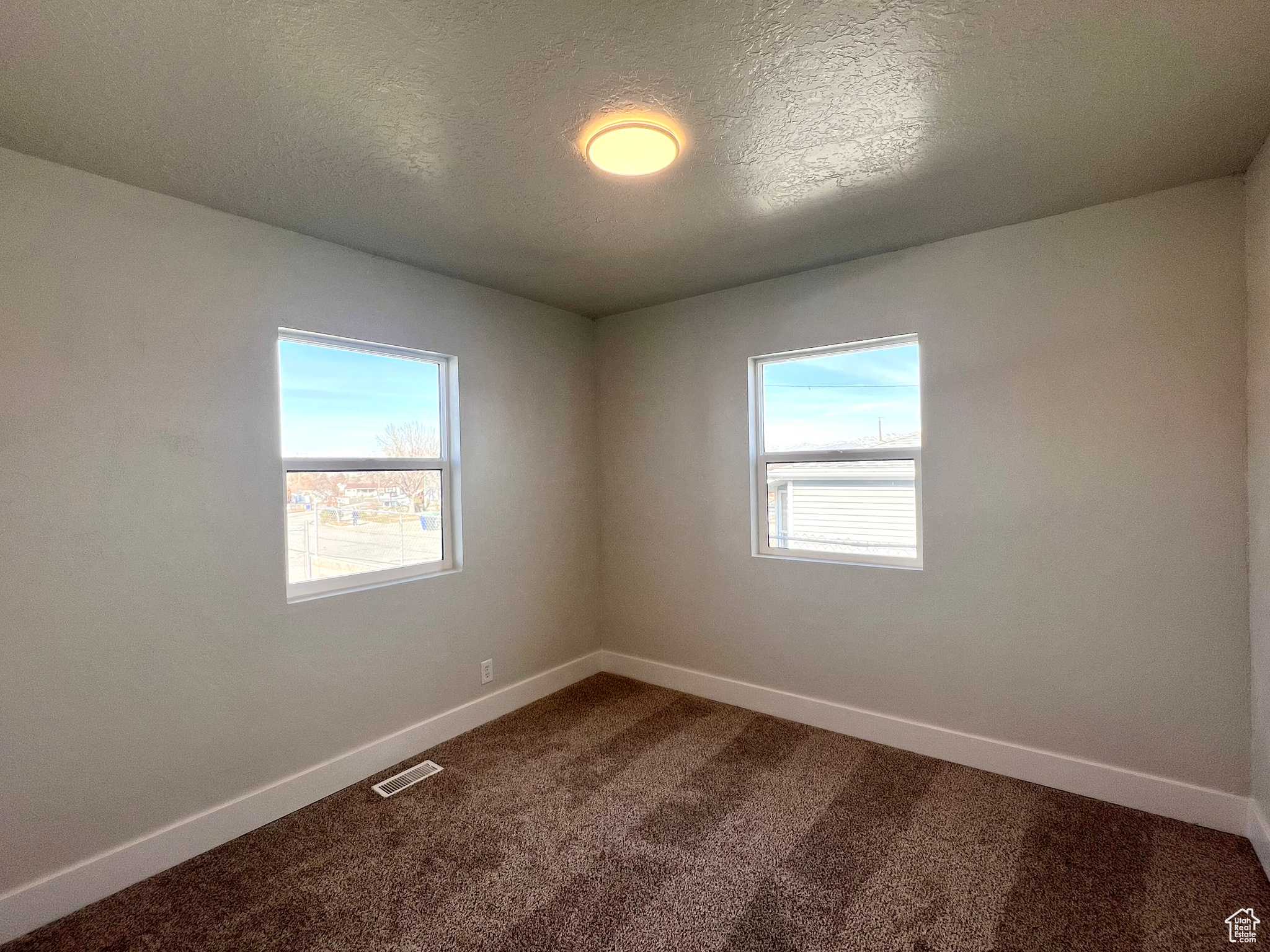 Unfurnished room with carpet and a textured ceiling