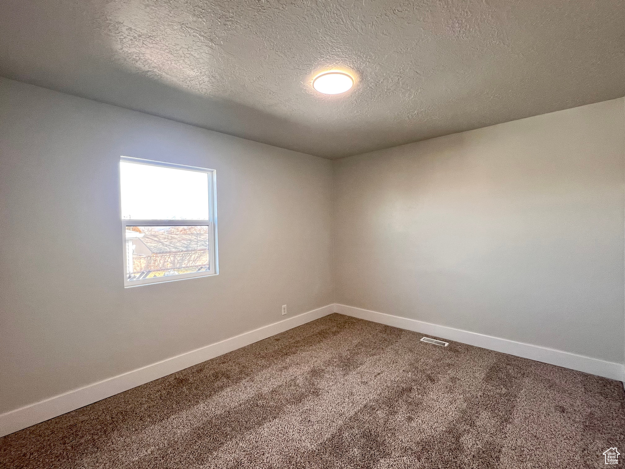 Unfurnished room with carpet and a textured ceiling