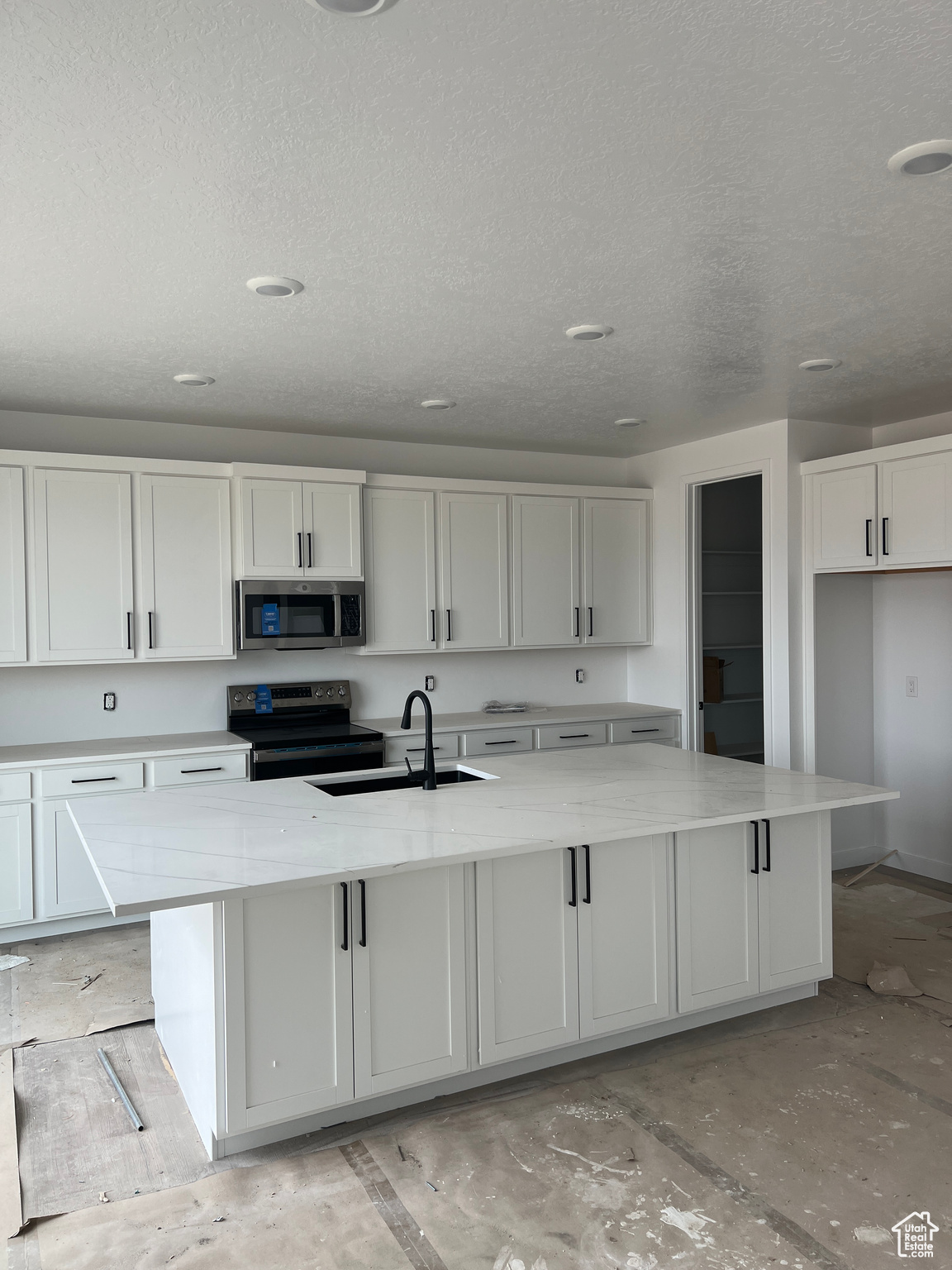 Kitchen featuring white cabinetry, a center island with sink, and appliances with stainless steel finishes