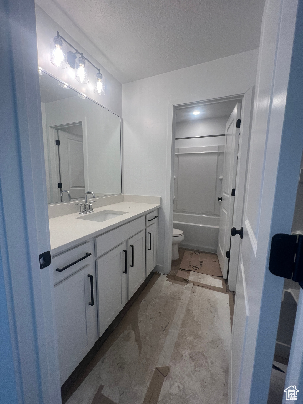 Full bathroom with vanity,  shower combination, toilet, and a textured ceiling