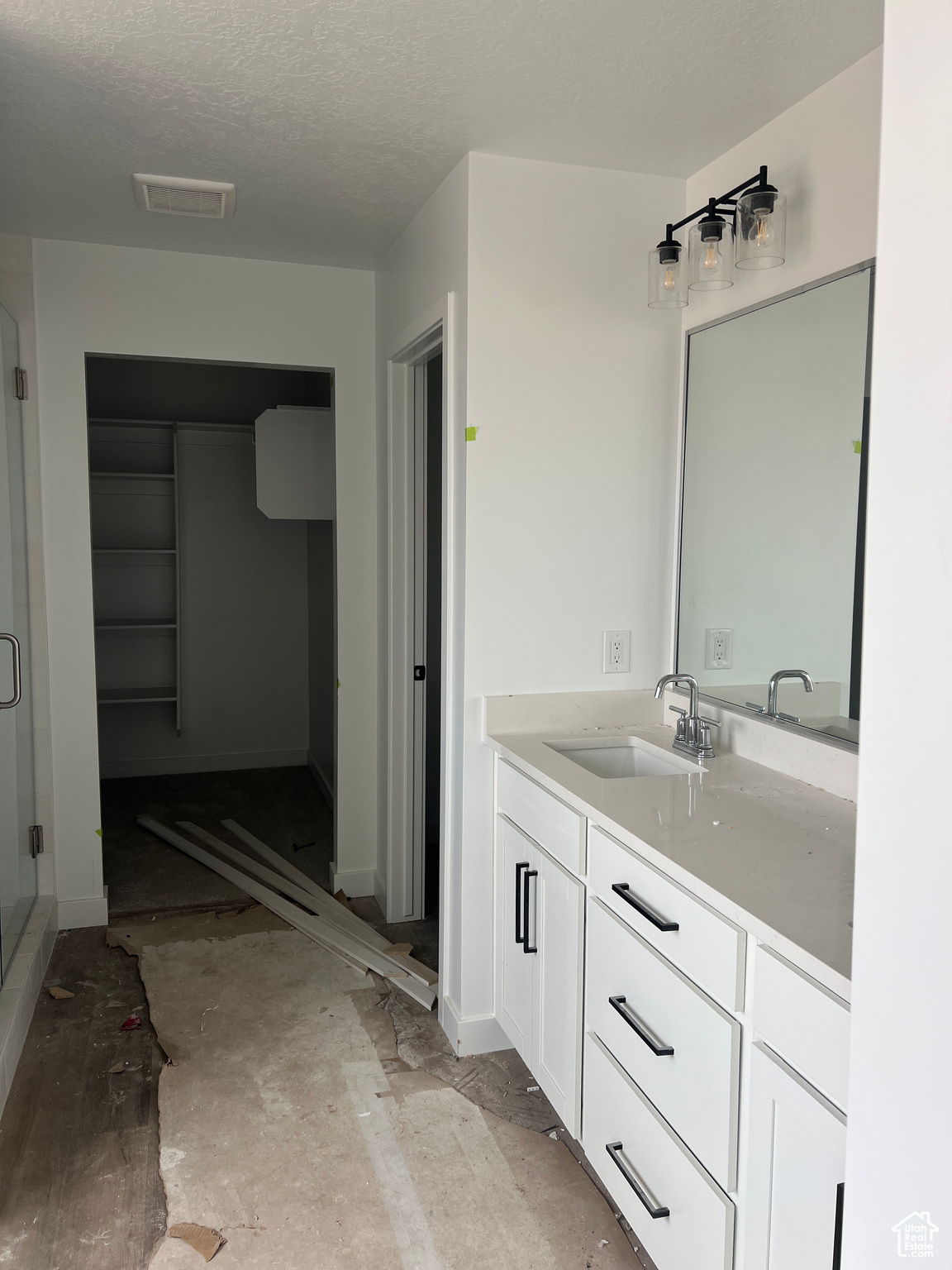 Bathroom featuring a textured ceiling, vanity, and an enclosed shower