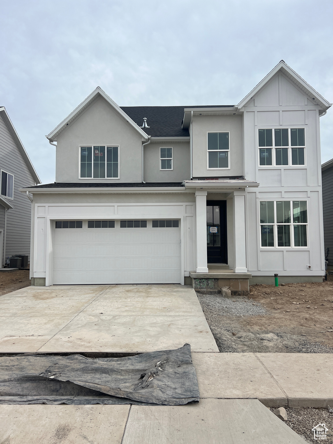 View of front of home with a garage and central AC