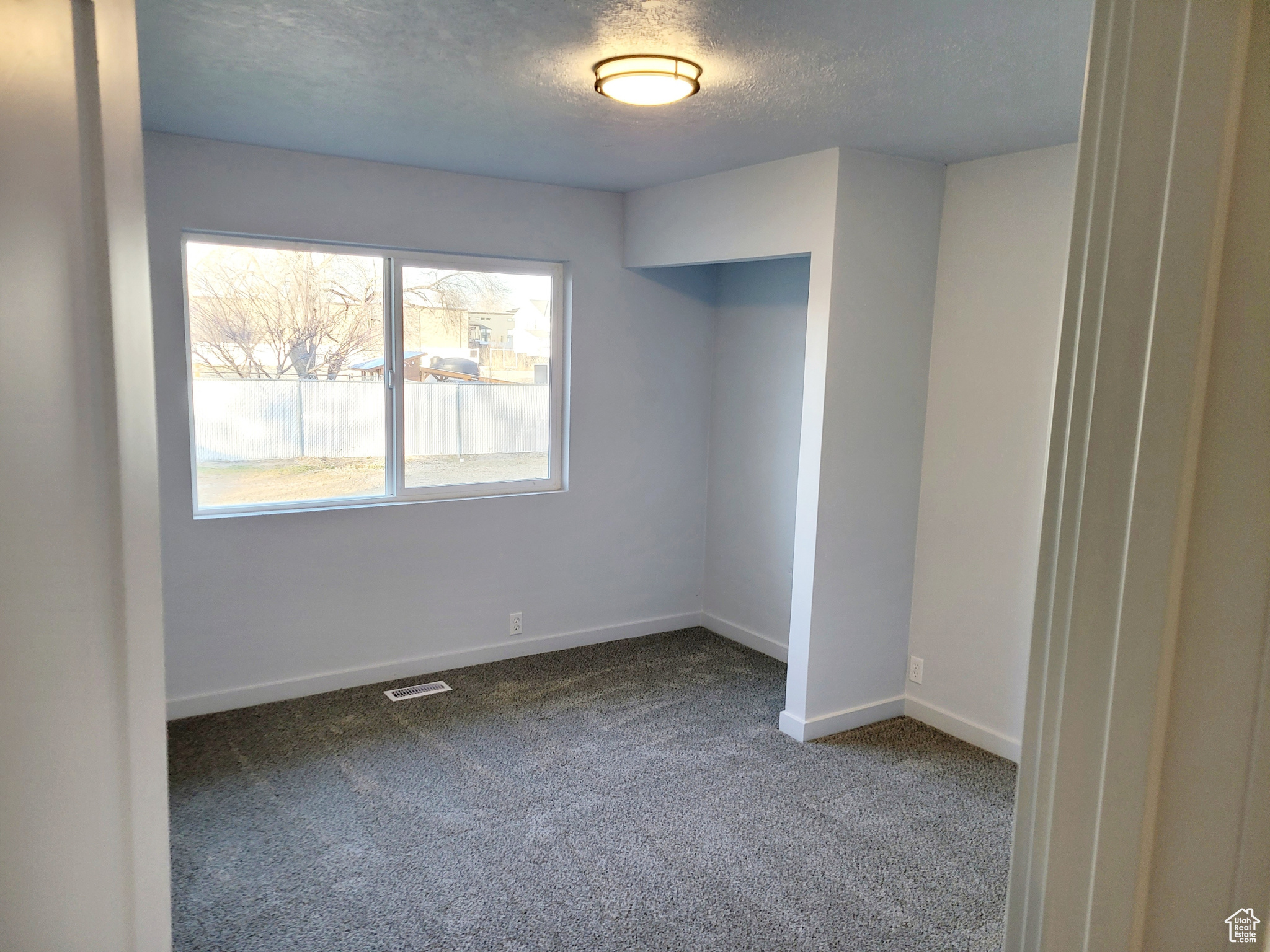 Carpeted empty room with a textured ceiling