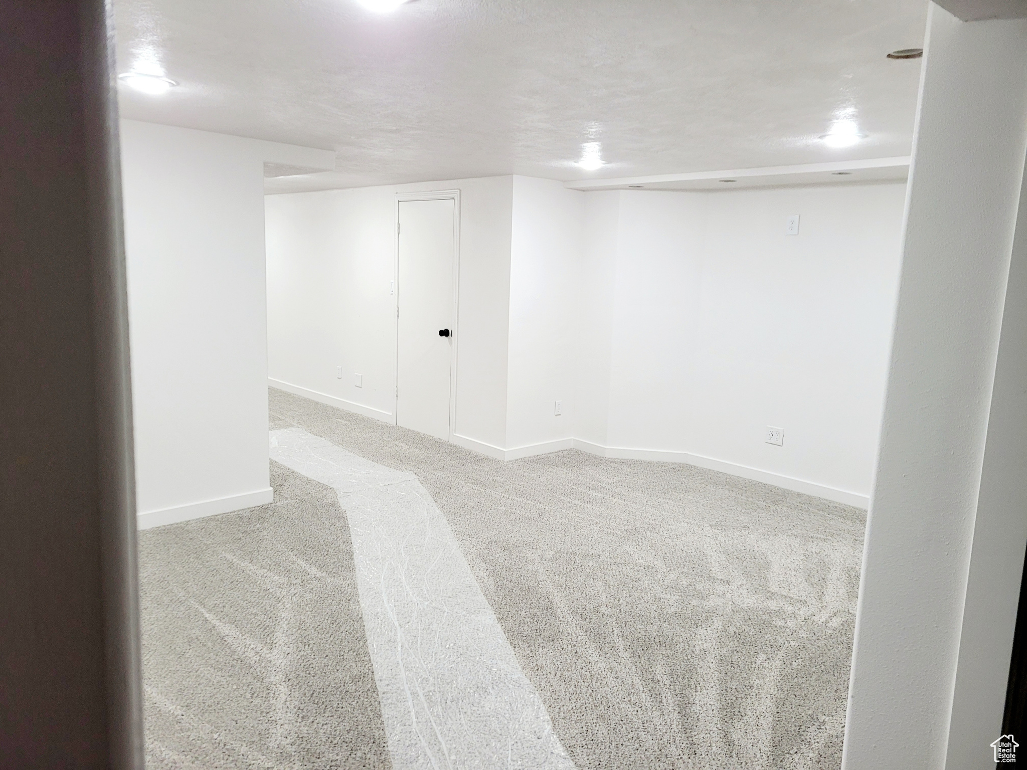 Empty room featuring a textured ceiling and light carpet