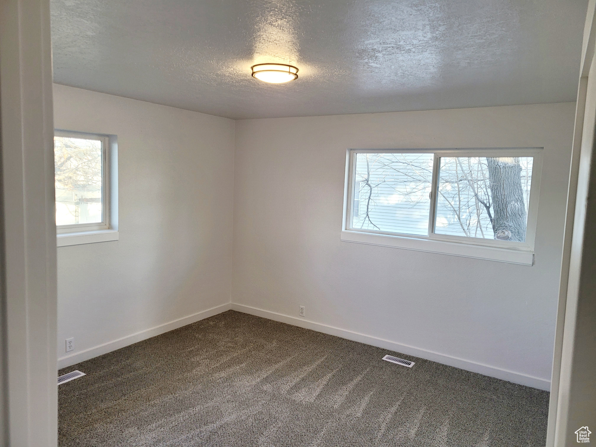 Unfurnished room with a textured ceiling and dark carpet