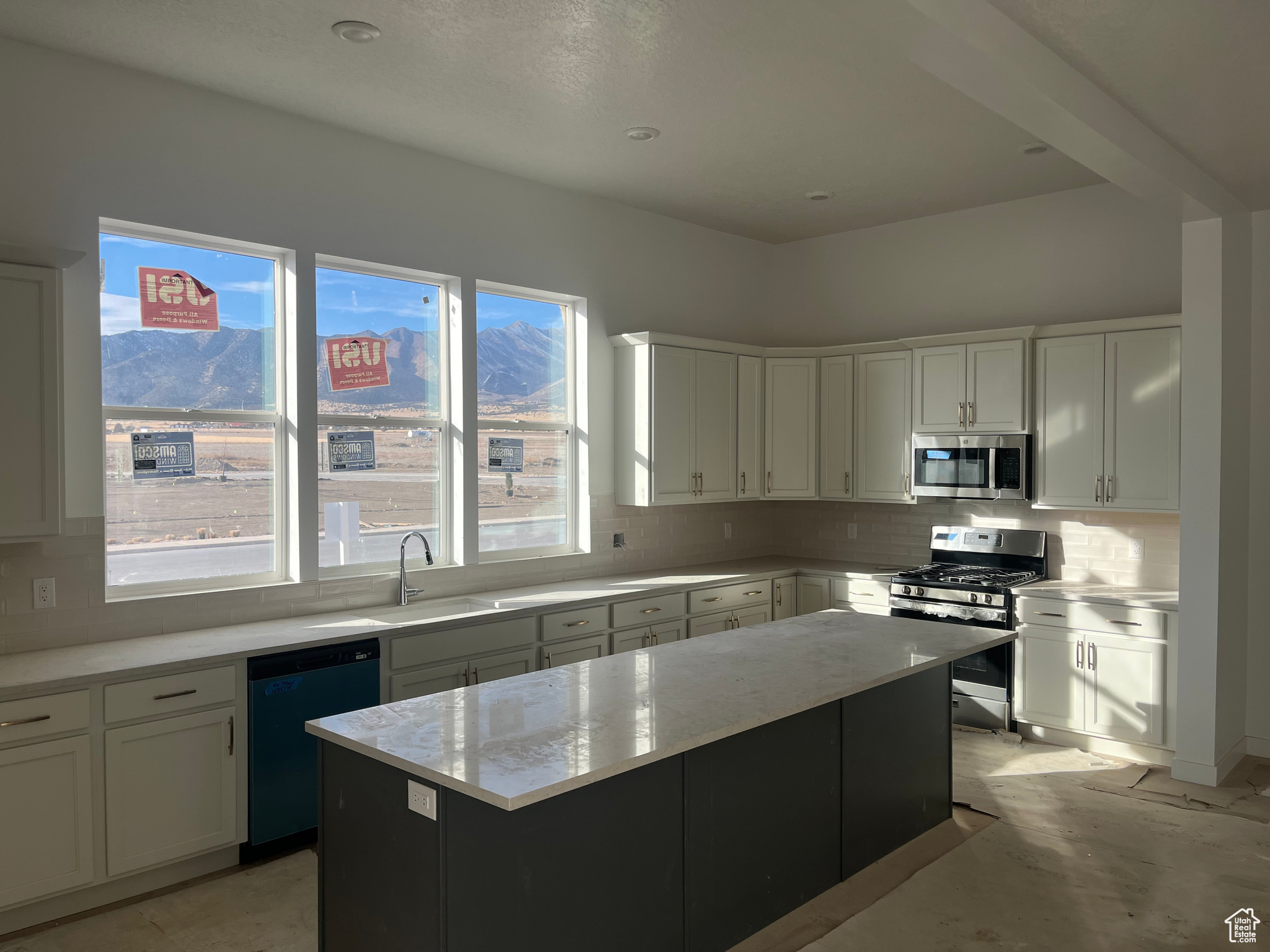 Kitchen with appliances with stainless steel finishes, sink, a mountain view, a center island, and white cabinetry