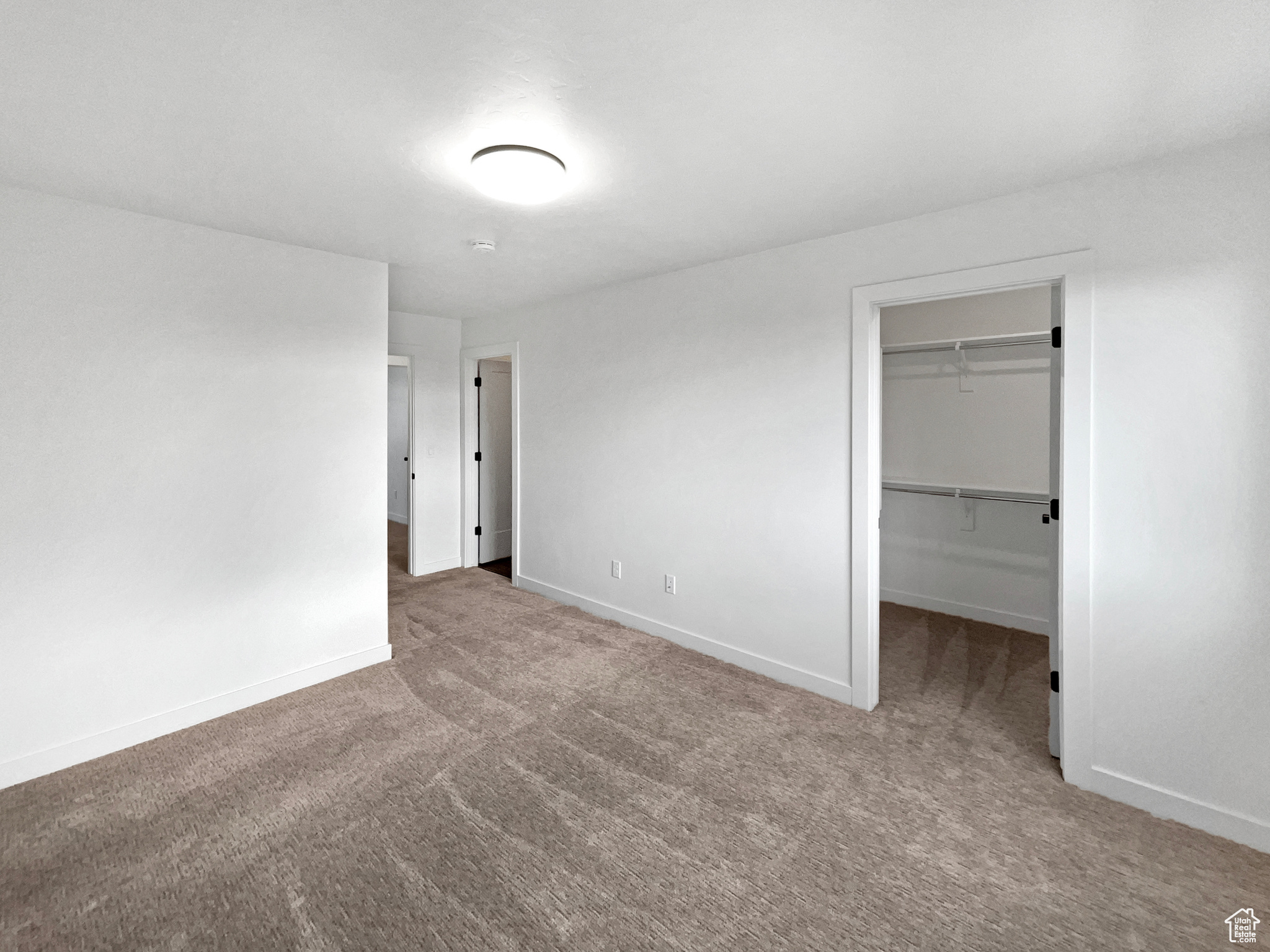 Unfurnished bedroom featuring carpet flooring, a spacious closet, and a closet