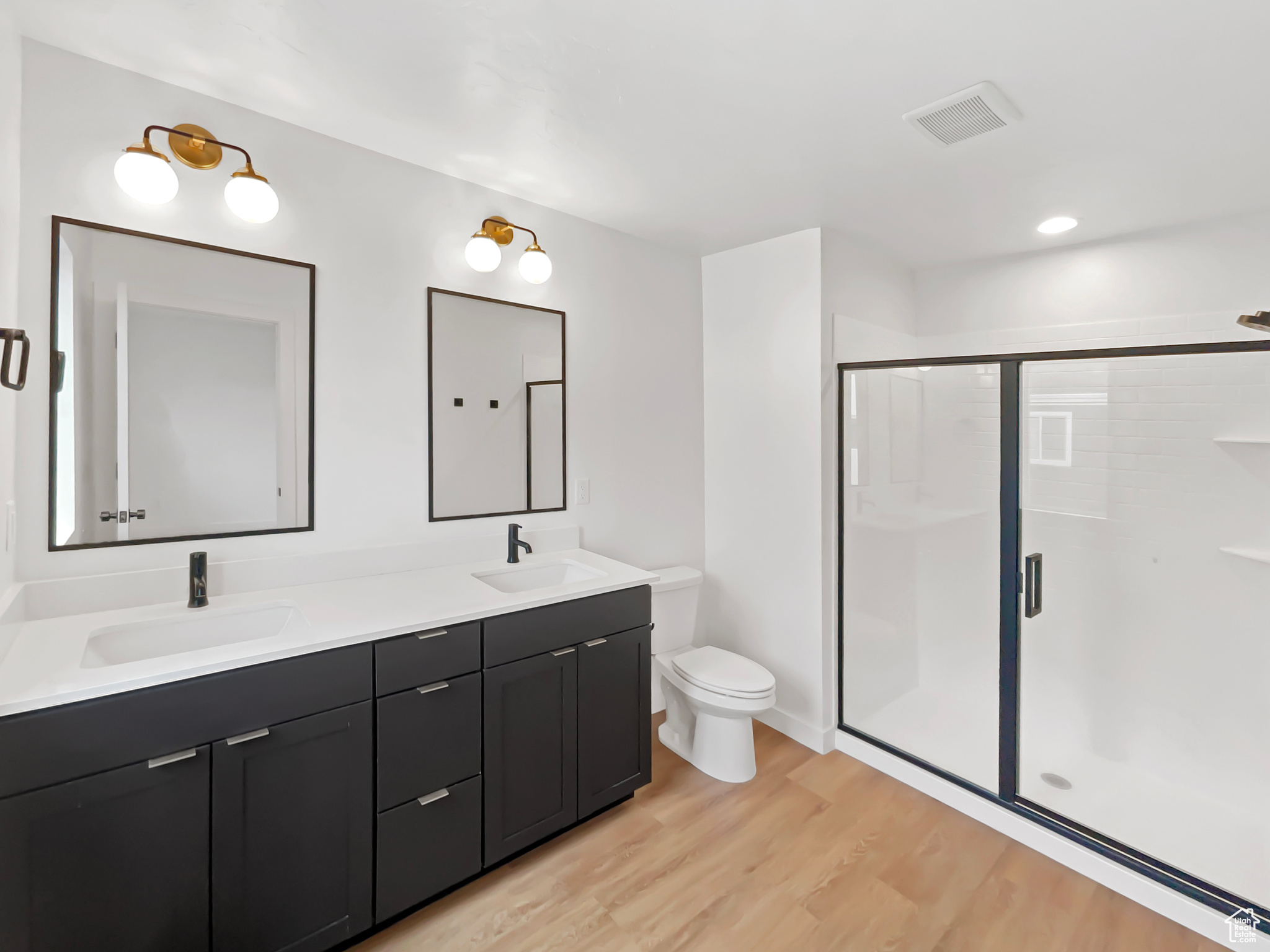 Bathroom with vanity, toilet, an enclosed shower, and wood-type flooring