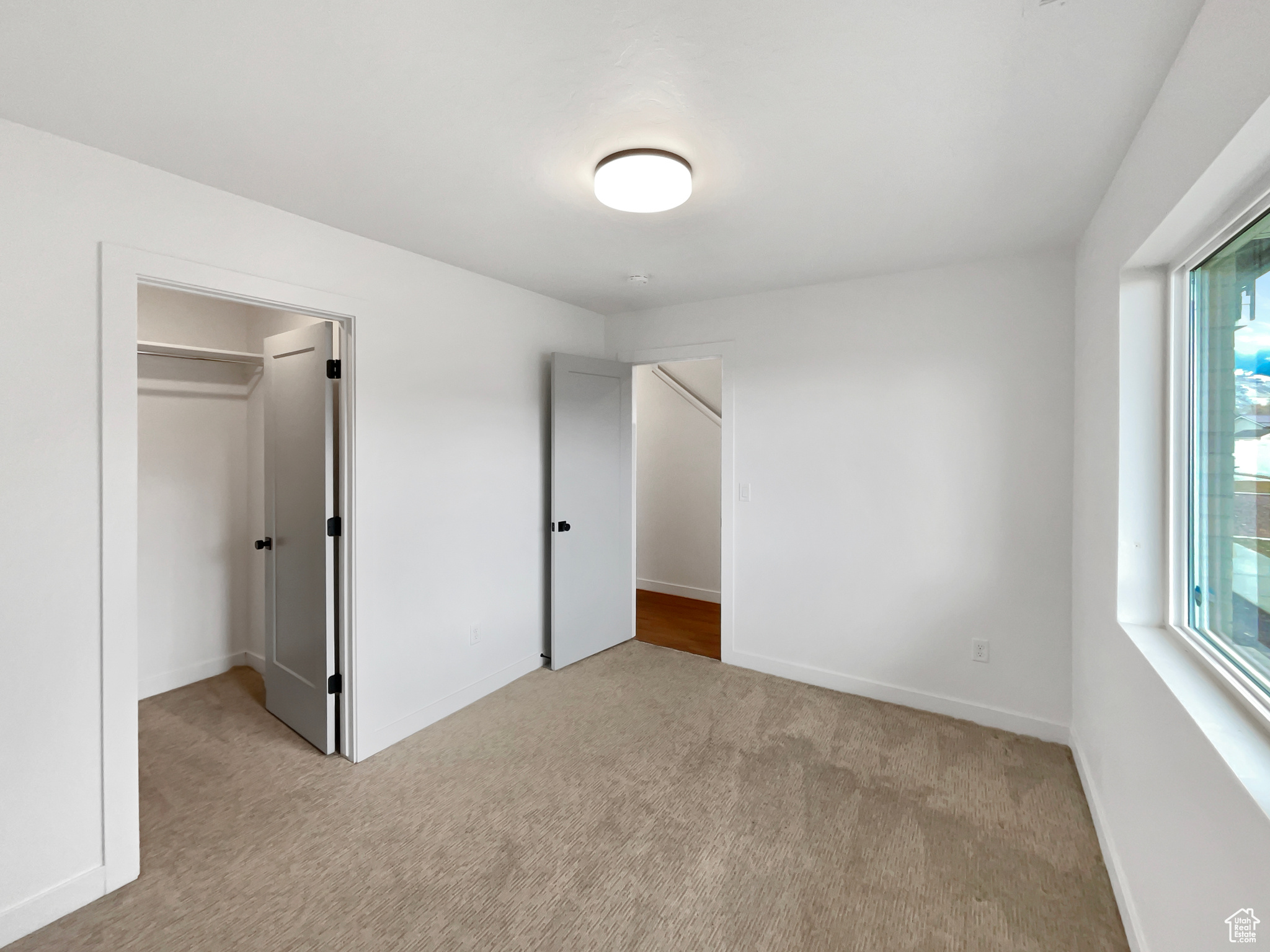 Unfurnished bedroom featuring a closet and light colored carpet