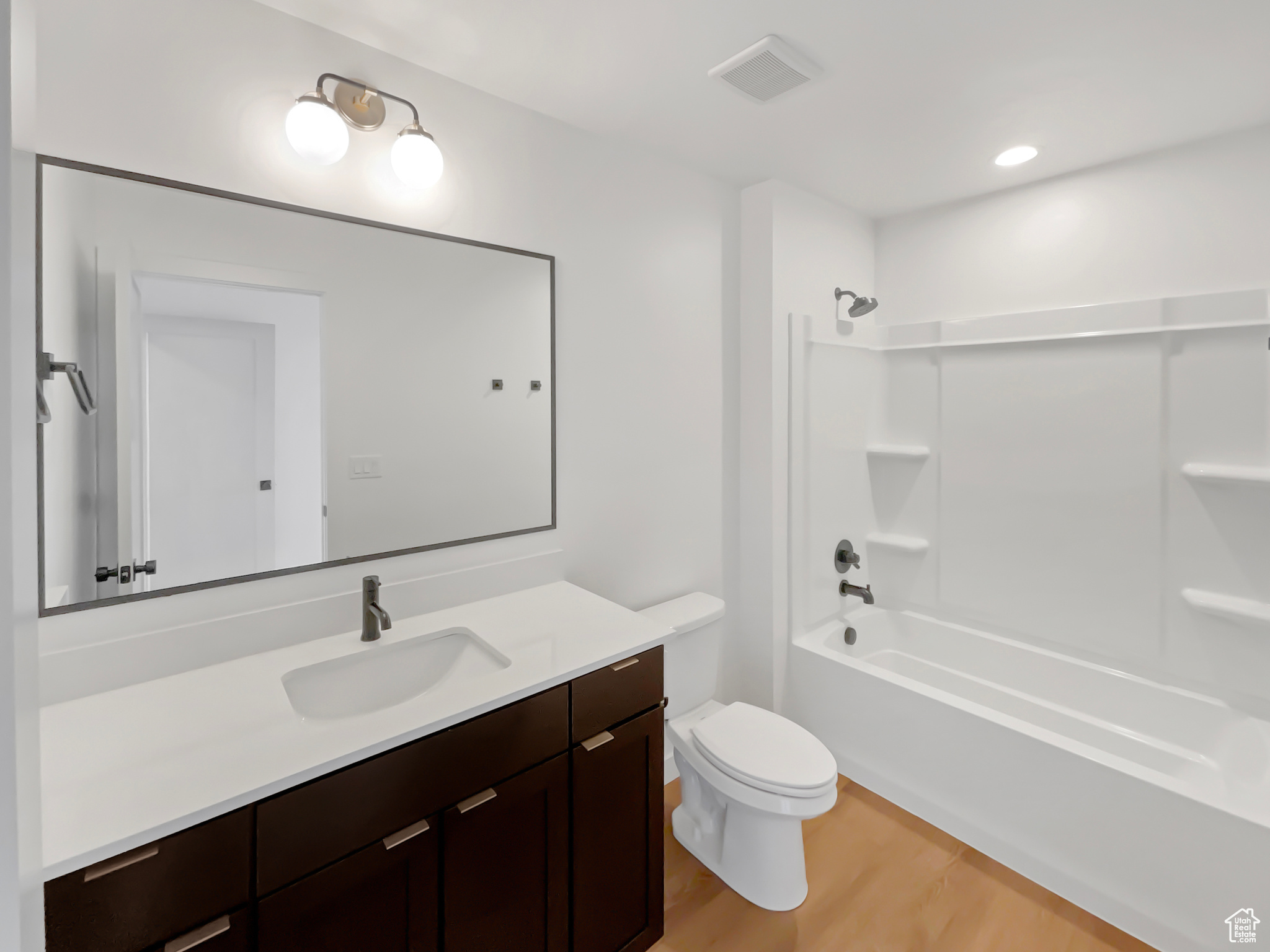 Full bathroom with wood-type flooring, vanity, toilet, and shower / washtub combination