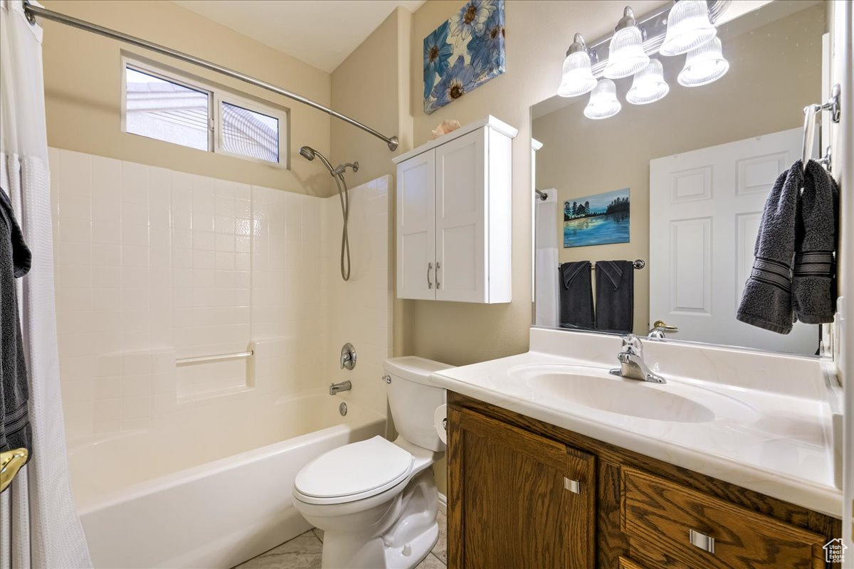 Full bathroom with vanity, shower / bath combo, and toilet