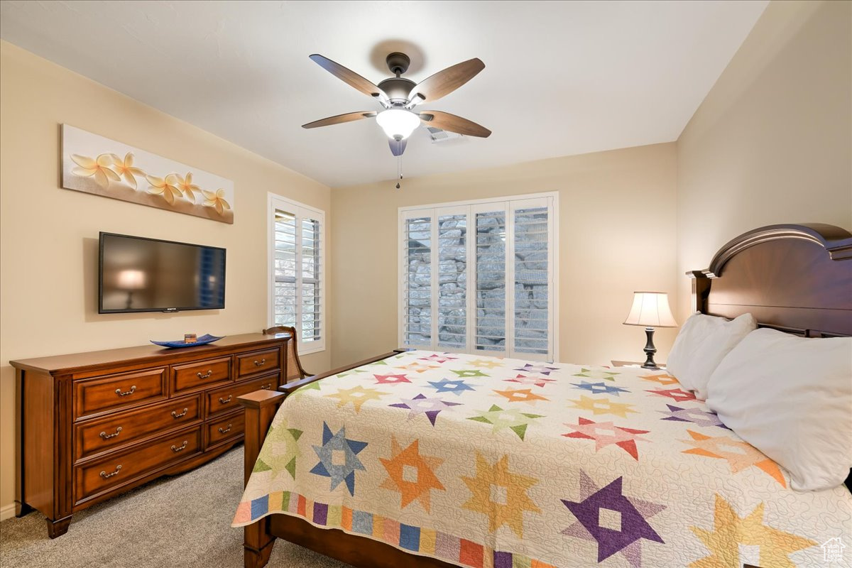 Carpeted bedroom featuring ceiling fan