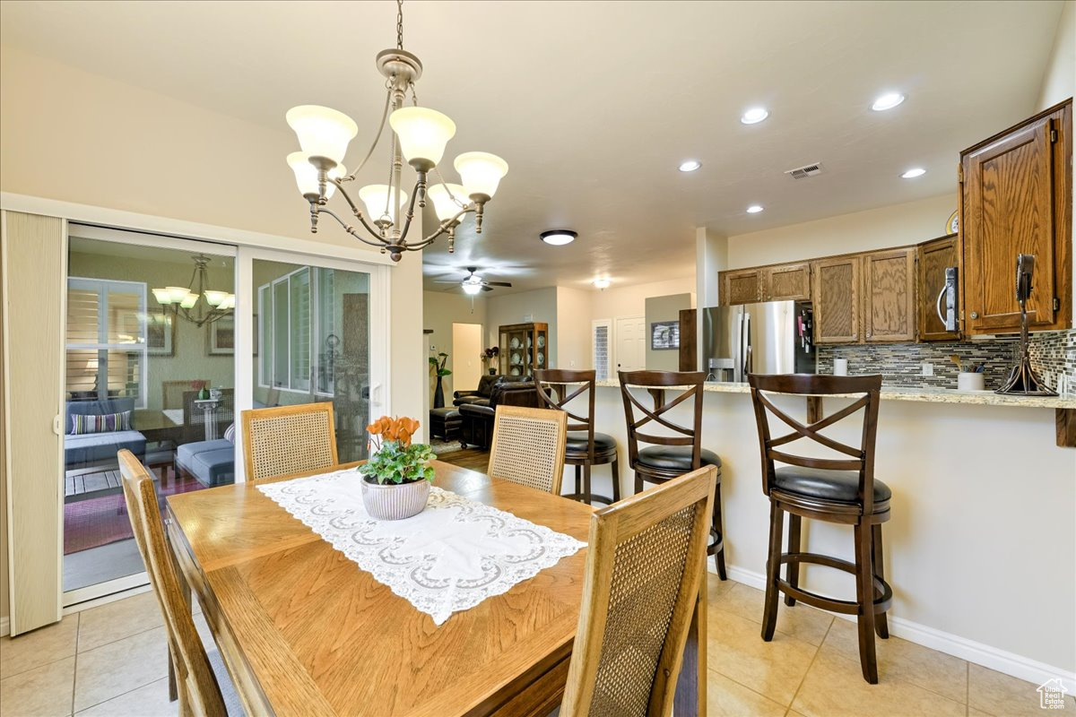 Tiled dining area with ceiling fan with notable chandelier