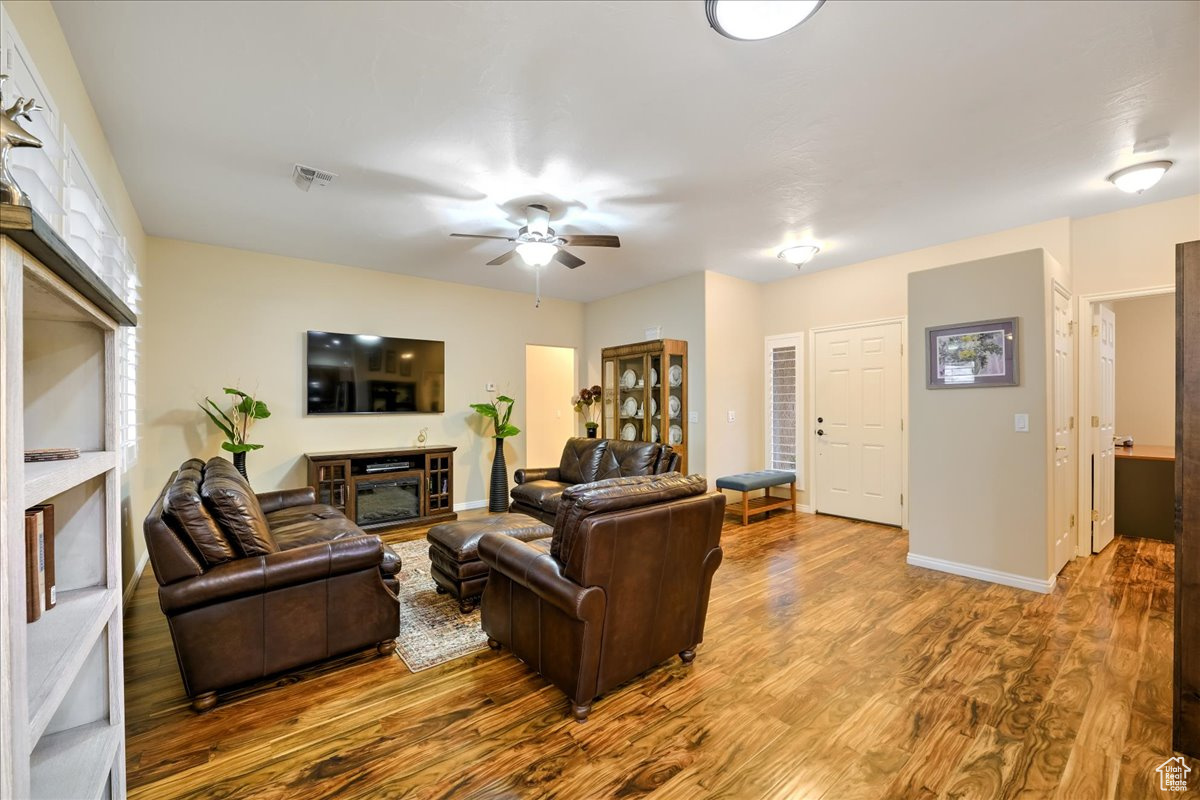 Living room with ceiling fan, wood-type flooring, and a fireplace