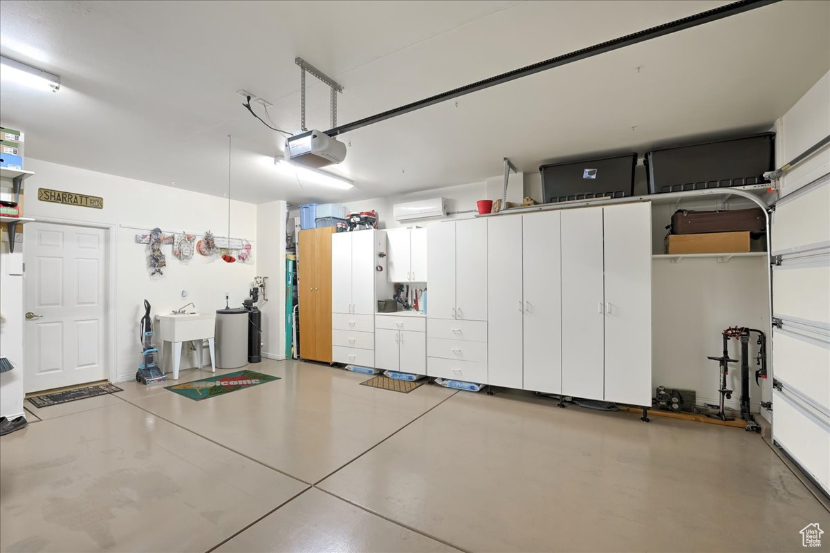 Garage featuring an AC wall unit, sink, and a garage door opener