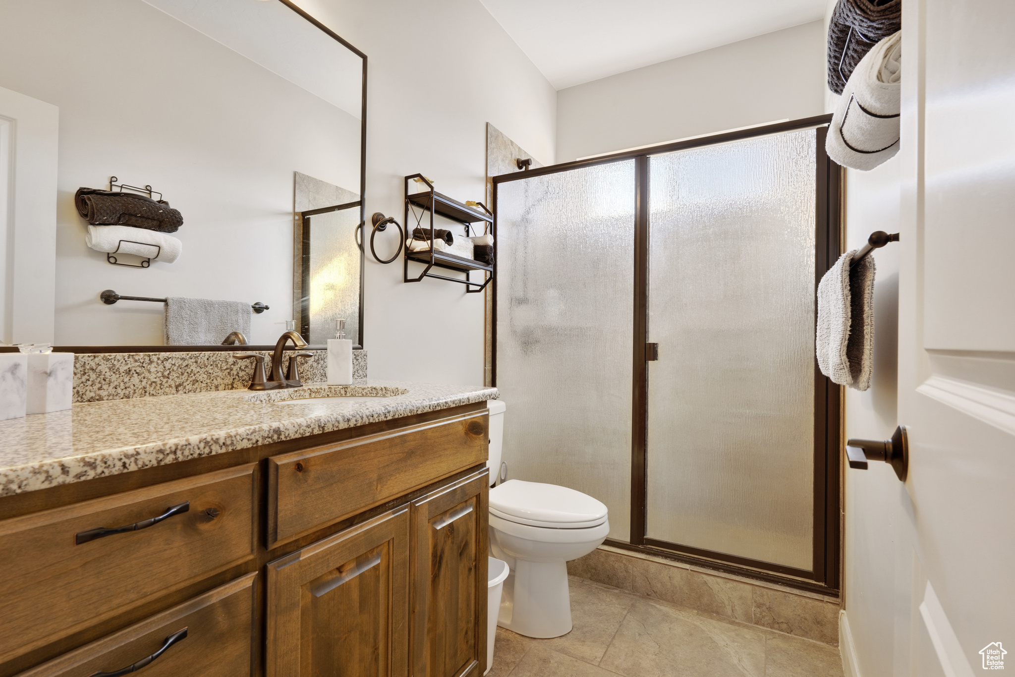 Bathroom with tile patterned flooring, vanity, toilet, and a shower with door