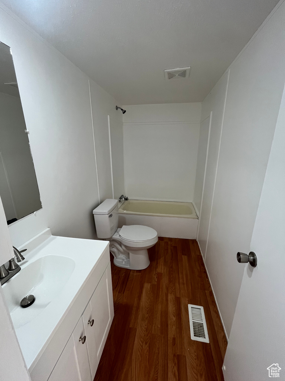 Full bathroom with bathing tub / shower combination, hardwood / wood-style floors, vanity, and toilet