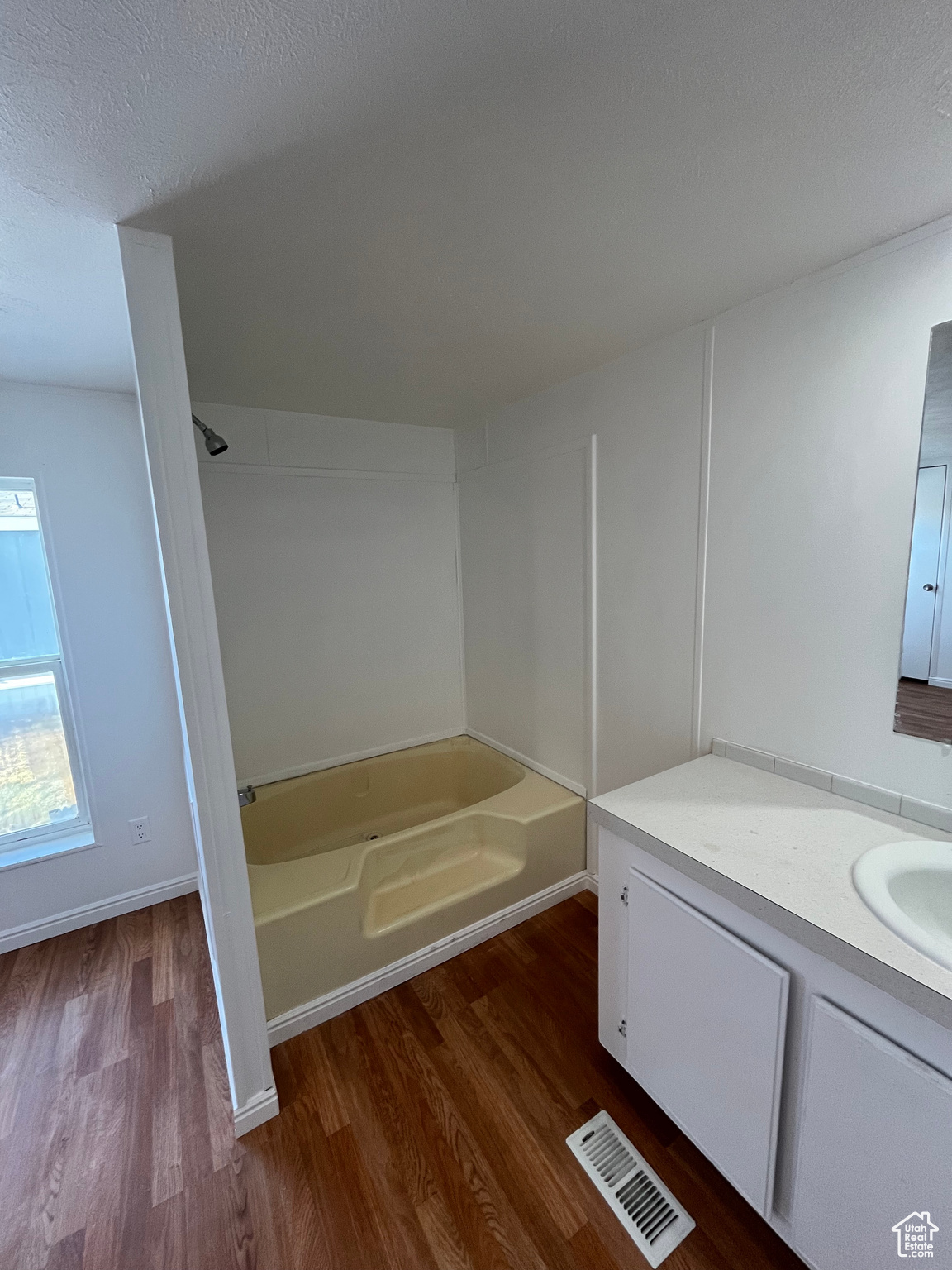 Bathroom with wood-type flooring, vanity, a textured ceiling, and shower / washtub combination