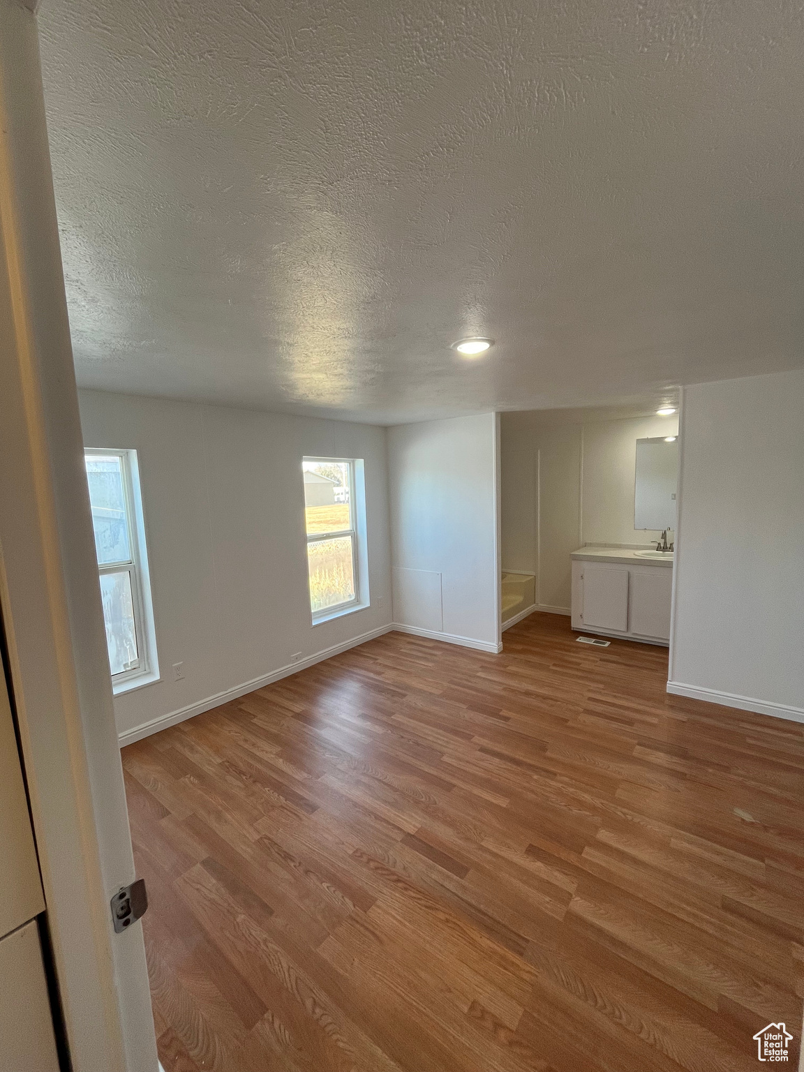 Empty room featuring light hardwood / wood-style flooring, a textured ceiling, and sink