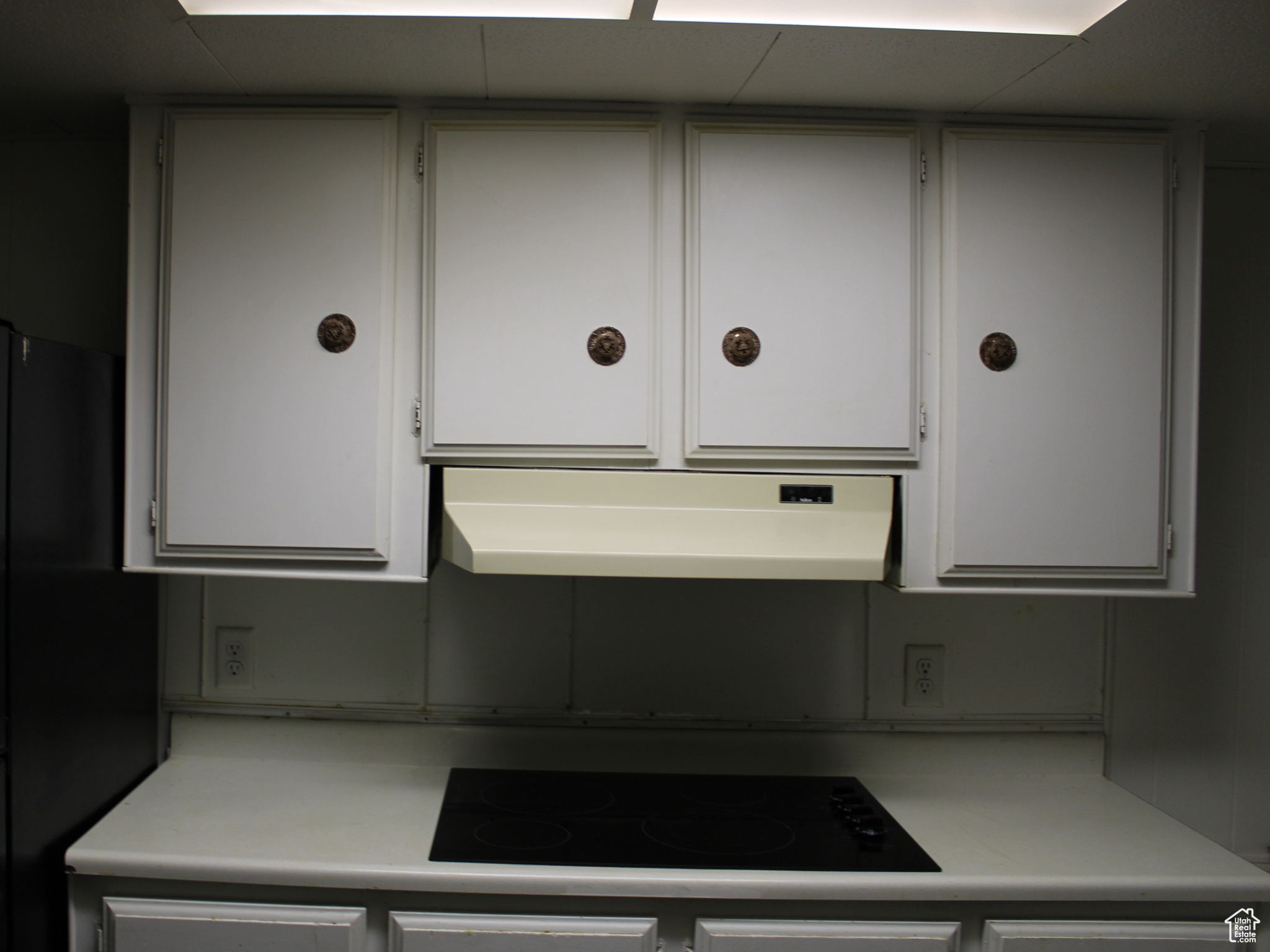 Kitchen with white cabinetry, black appliances, and ventilation hood