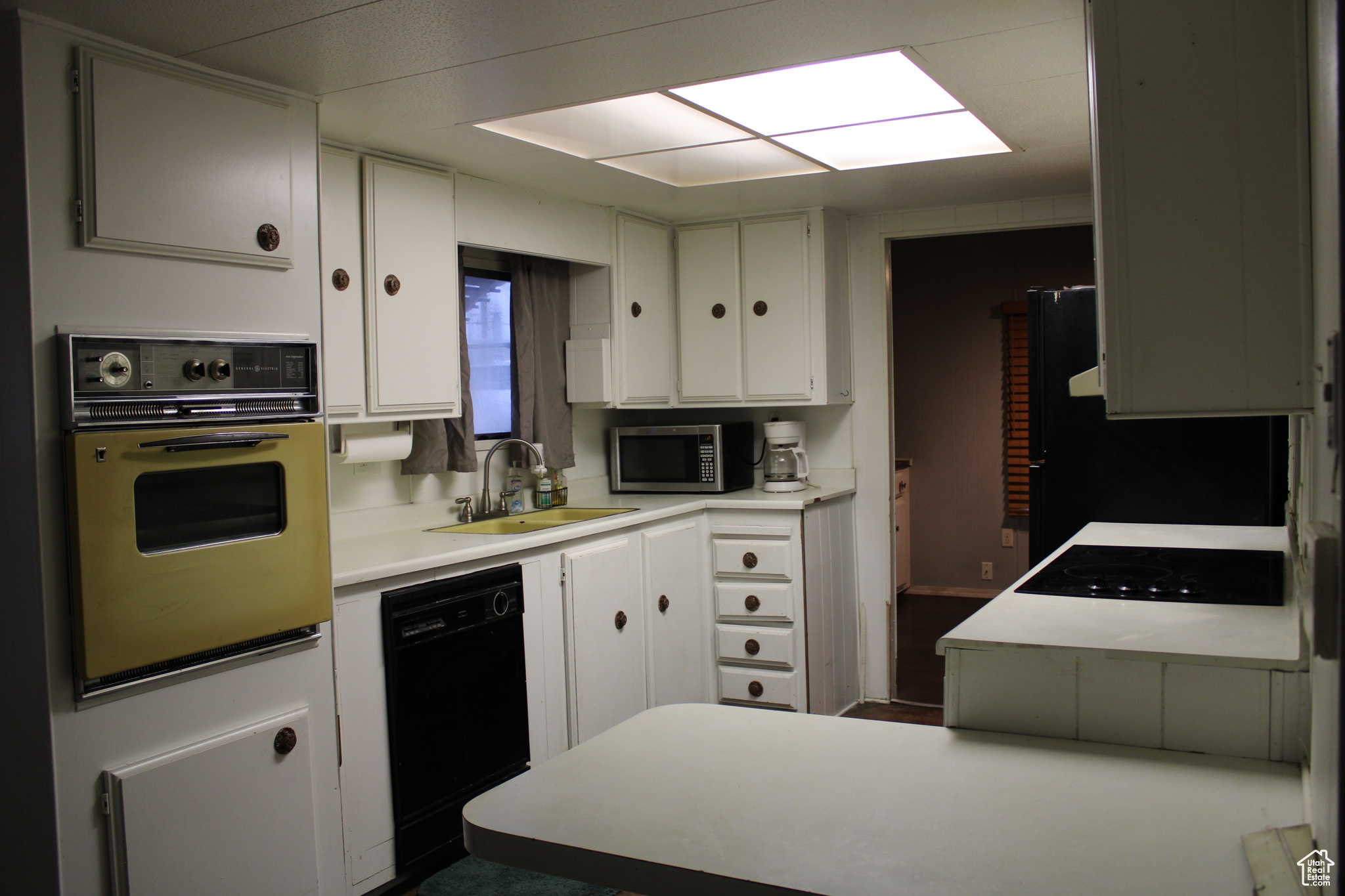 Kitchen with white cabinets, sink, and black appliances