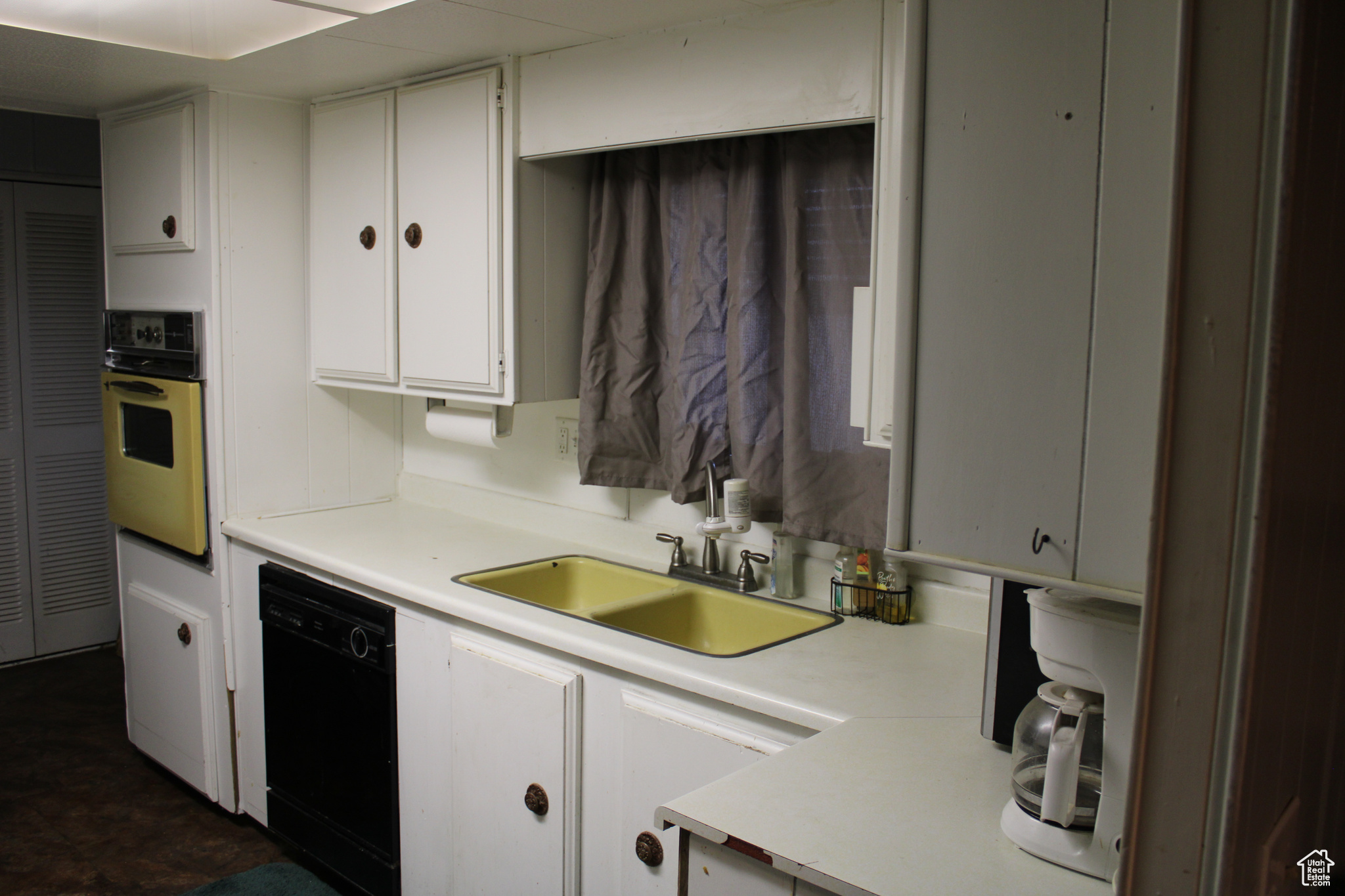 Kitchen featuring sink, white cabinets, and black appliances